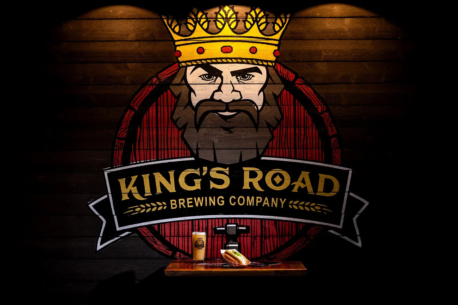 Specialty beer and hot dog on display in front of the giant King's Road Brewery Logo on the wall of their tasting room in Haddonfield NJ