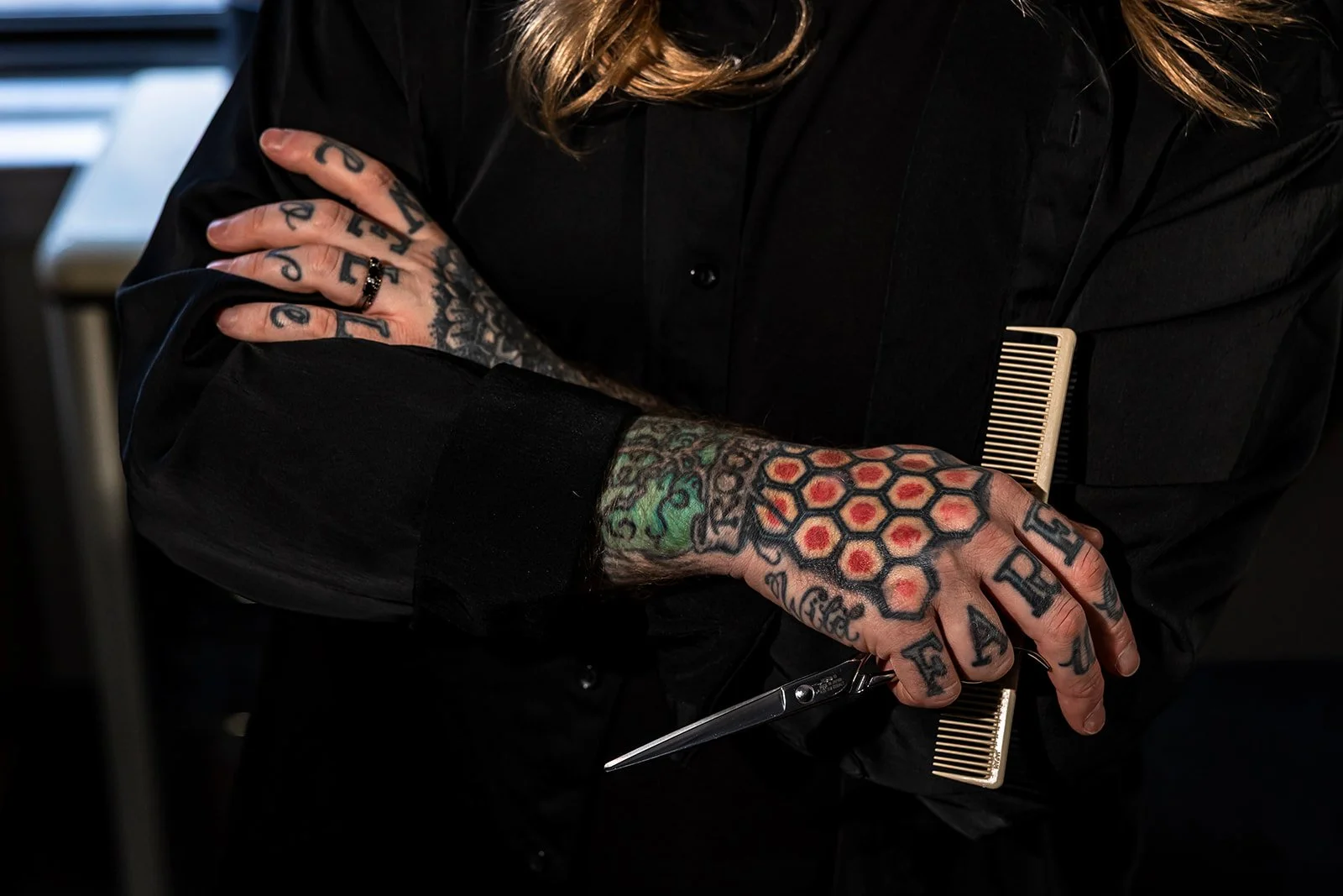 Close up of hands, tattoos, and hairstylists tools