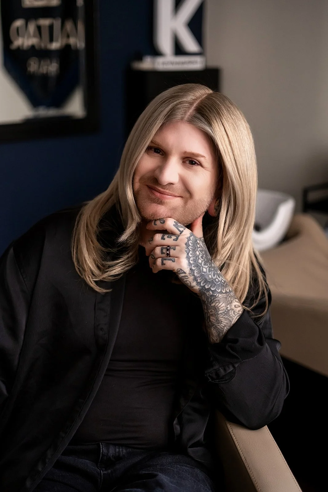 A salon owner's branding portraits in his new space, he is smiling at the camera, with his head in his hand.