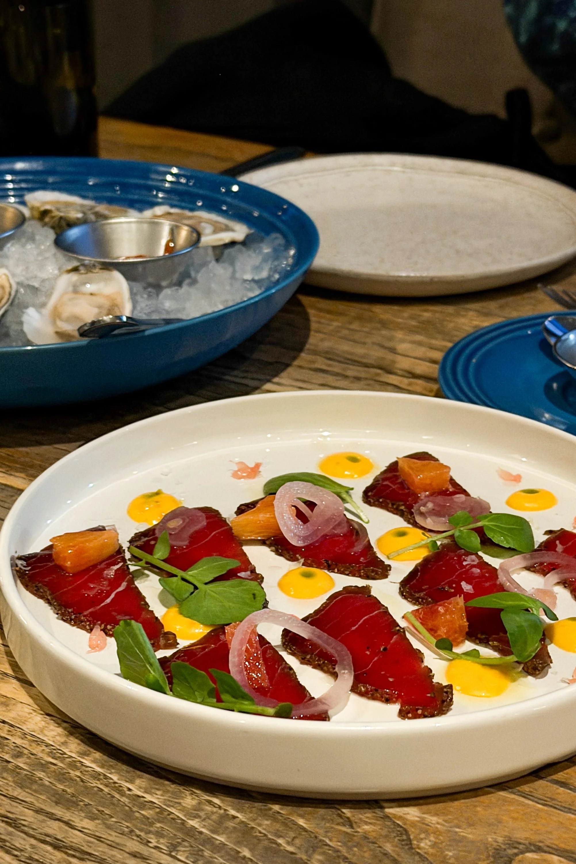 The Tuna Crudo at J.C. Holdway in Knoxville, topped with pickled onions and microgreens, with the Murder Point oysters in the background