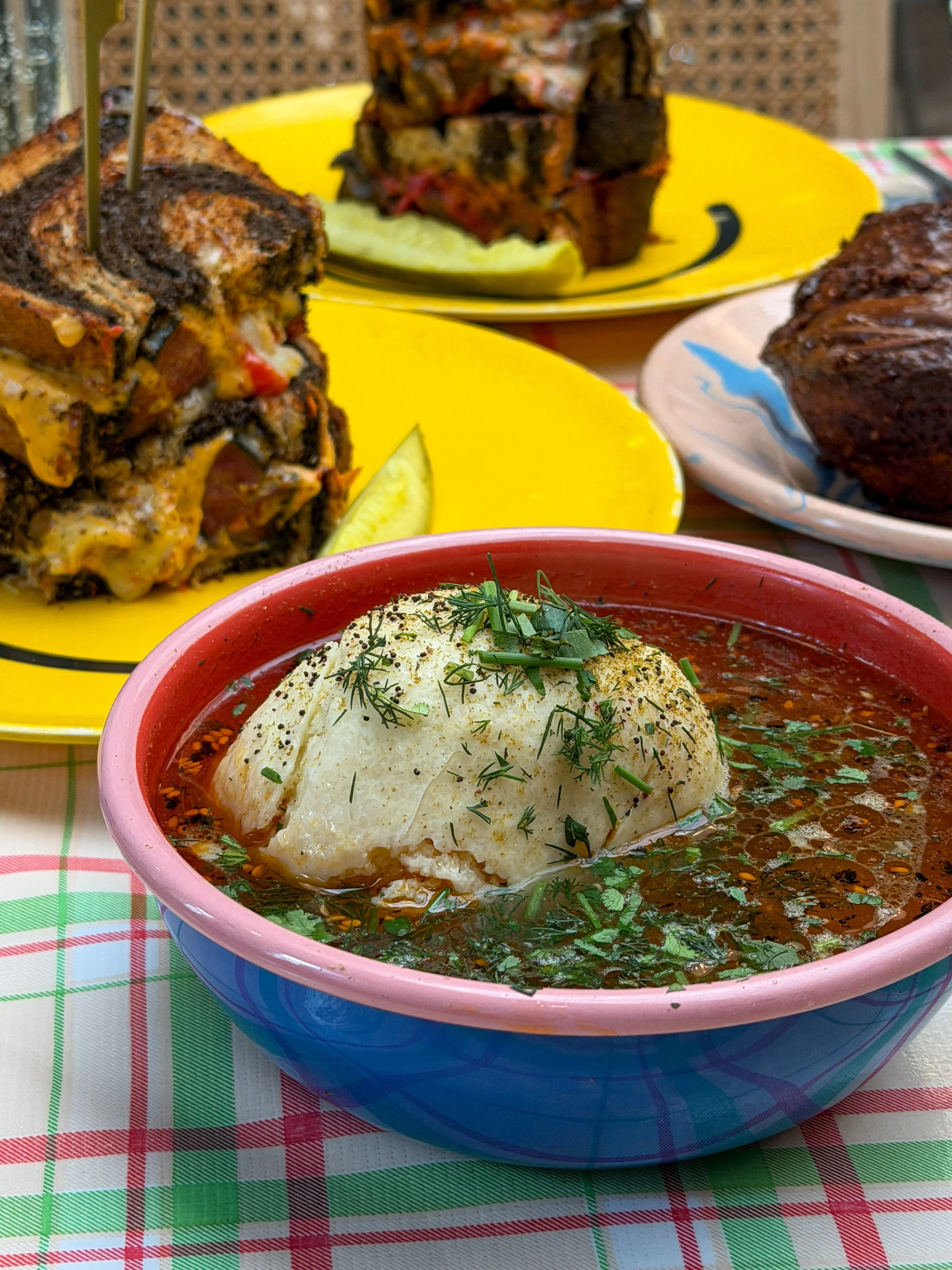 A close-up of the fussed-up matzoh ball soup at Potchke Deli in Knoxville, featuring an oversized matzoh ball in a spiced, herb-topped broth