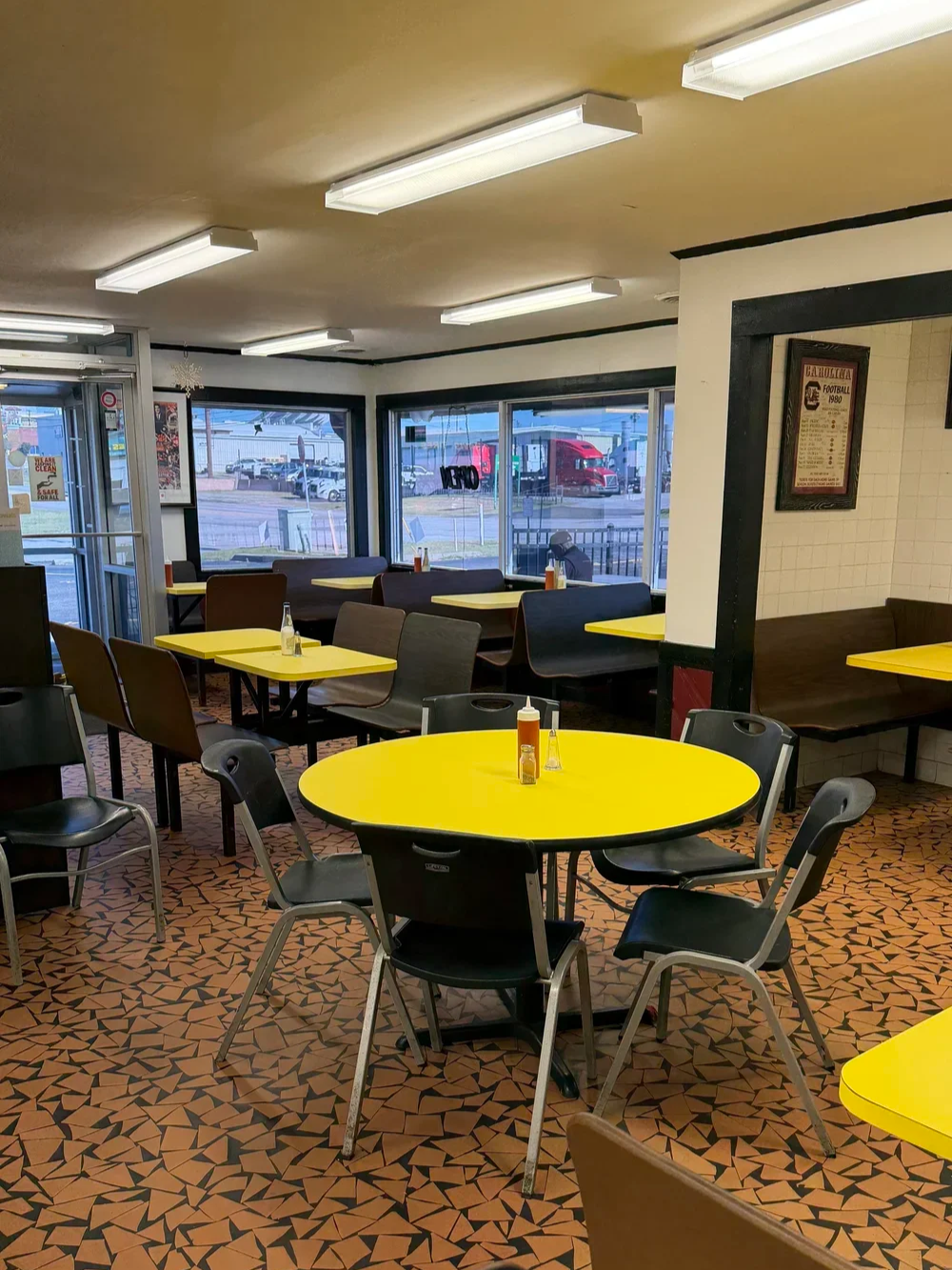 Dining room with yellow tables and black chairs at Bernie's Chicken in Columbia