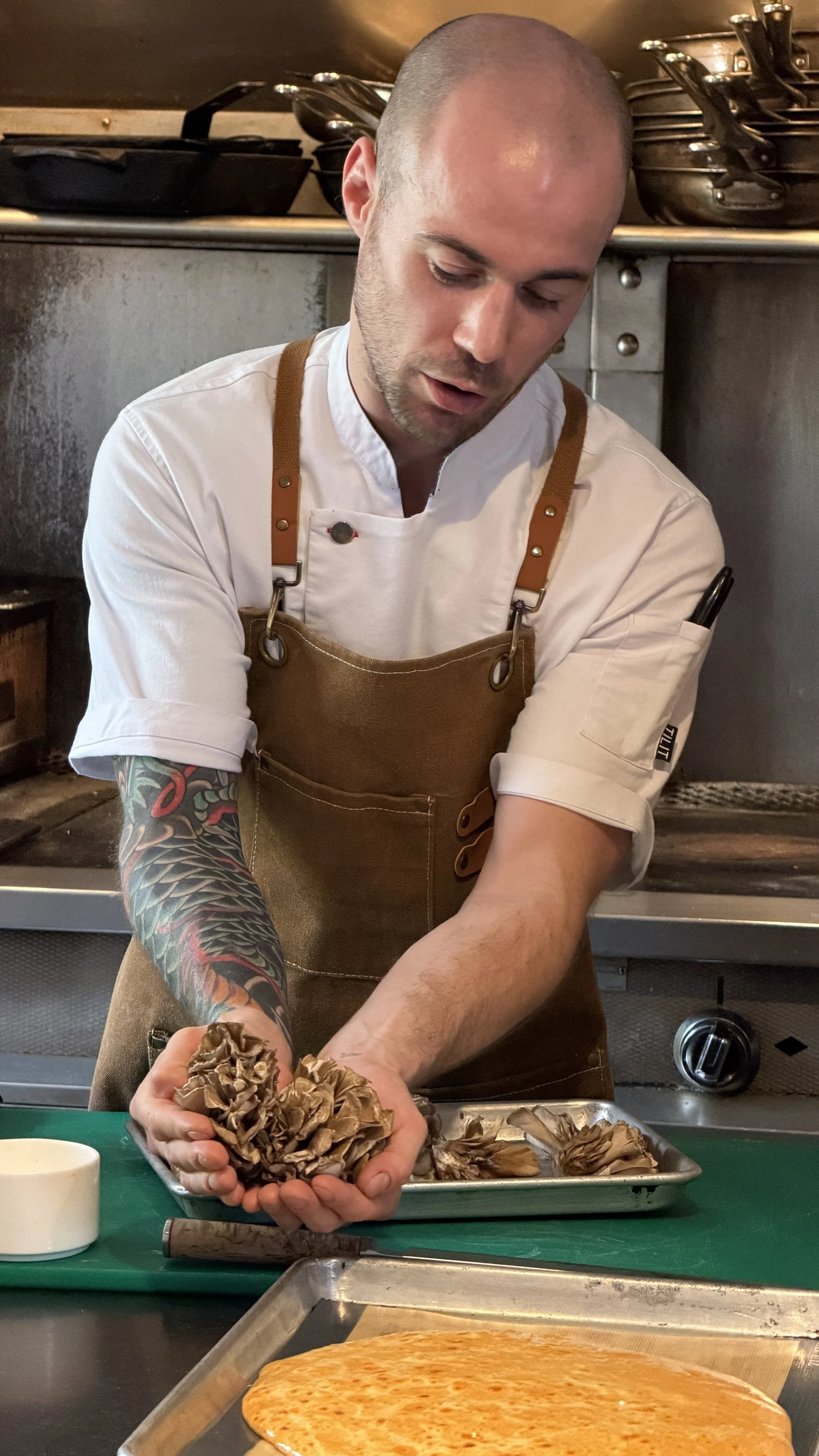 Chef Roberto holding fresh maitake mushrooms in the kitchen at Zero George
