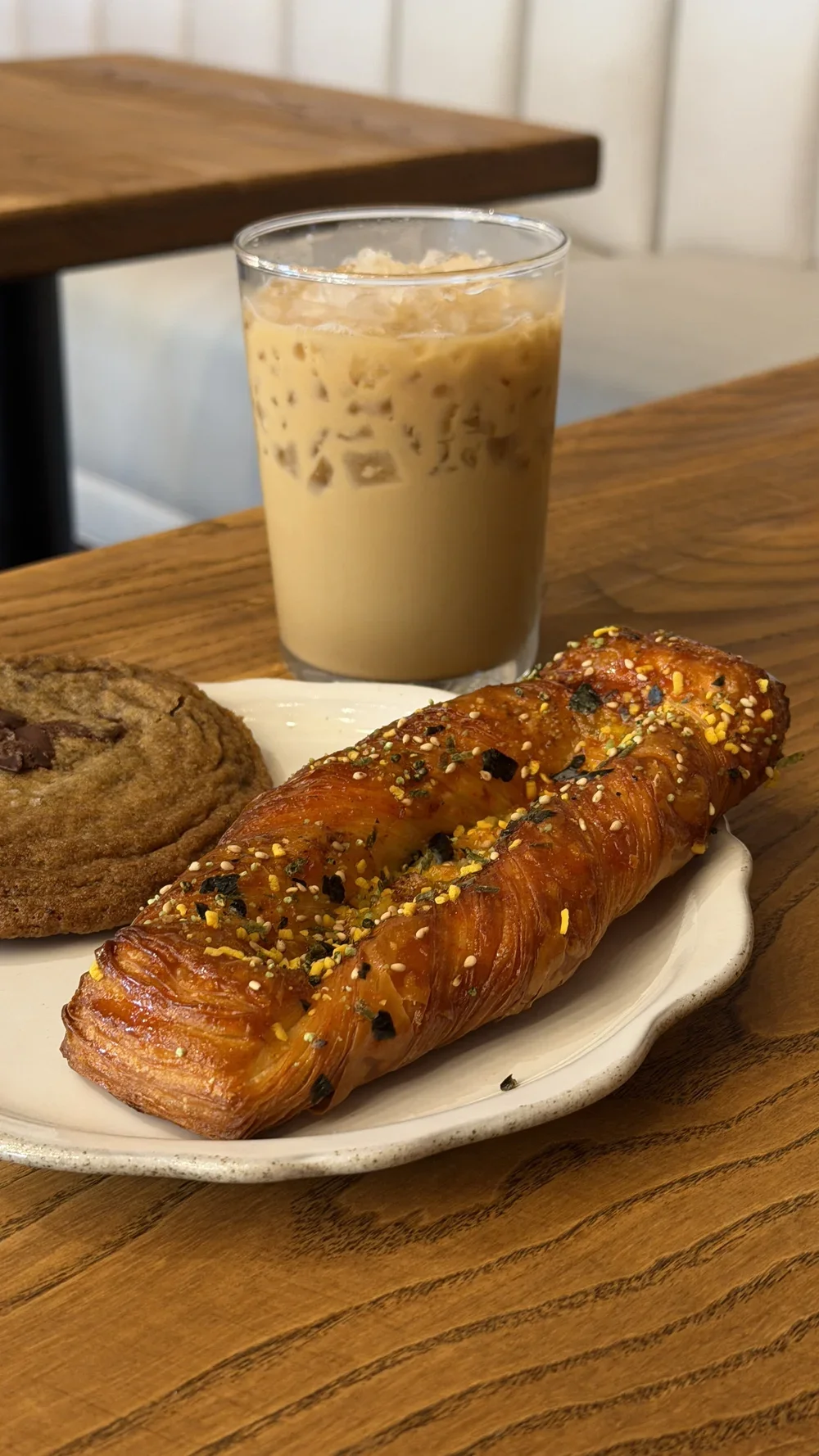 Gochujang pastry with sesame and citrus zest next to an iced latte and chocolate chip cookie at Nine of Cups