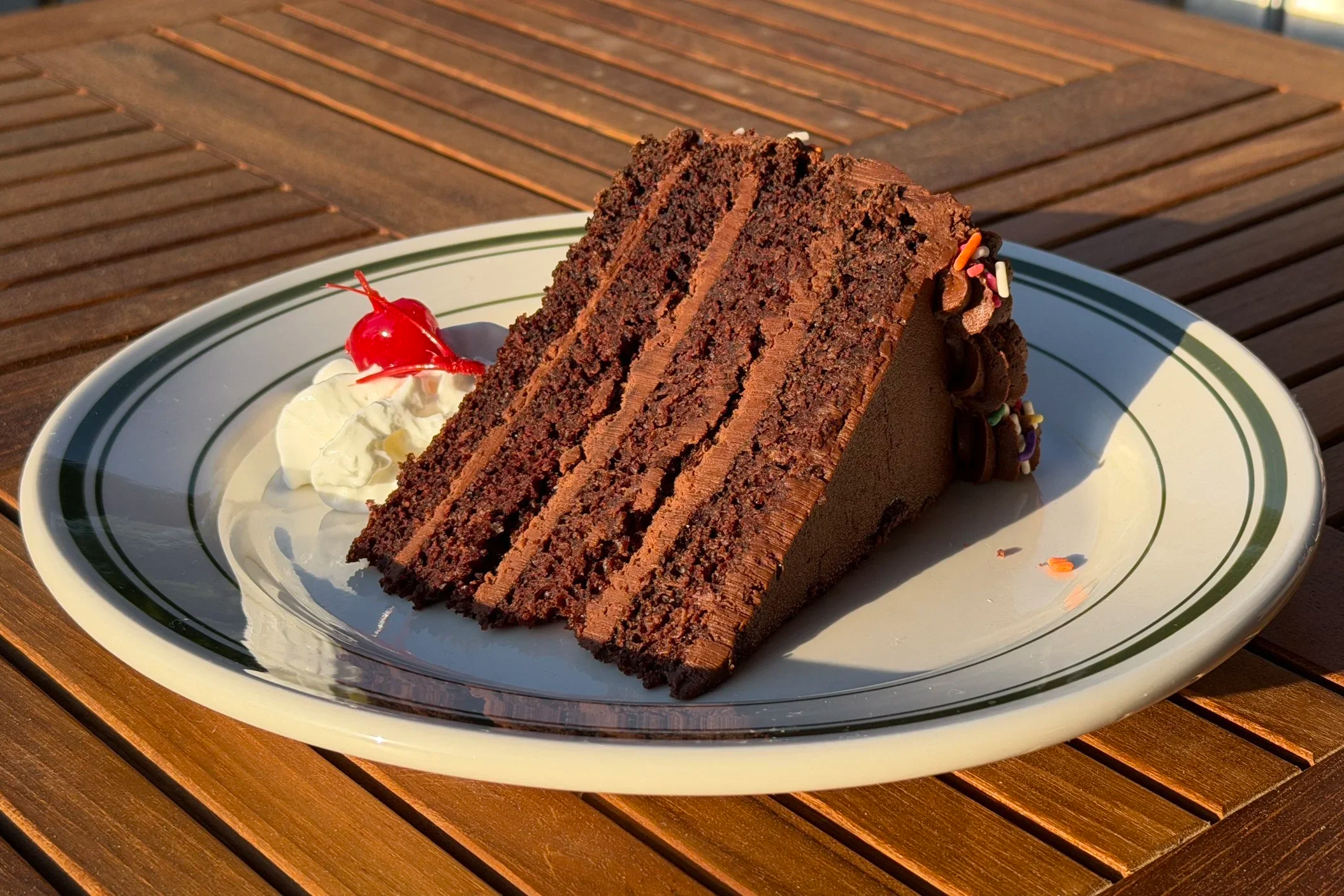 Slice of chocolate layer cake with whipped cream and a cherry at Grey's Diner in Charlotte