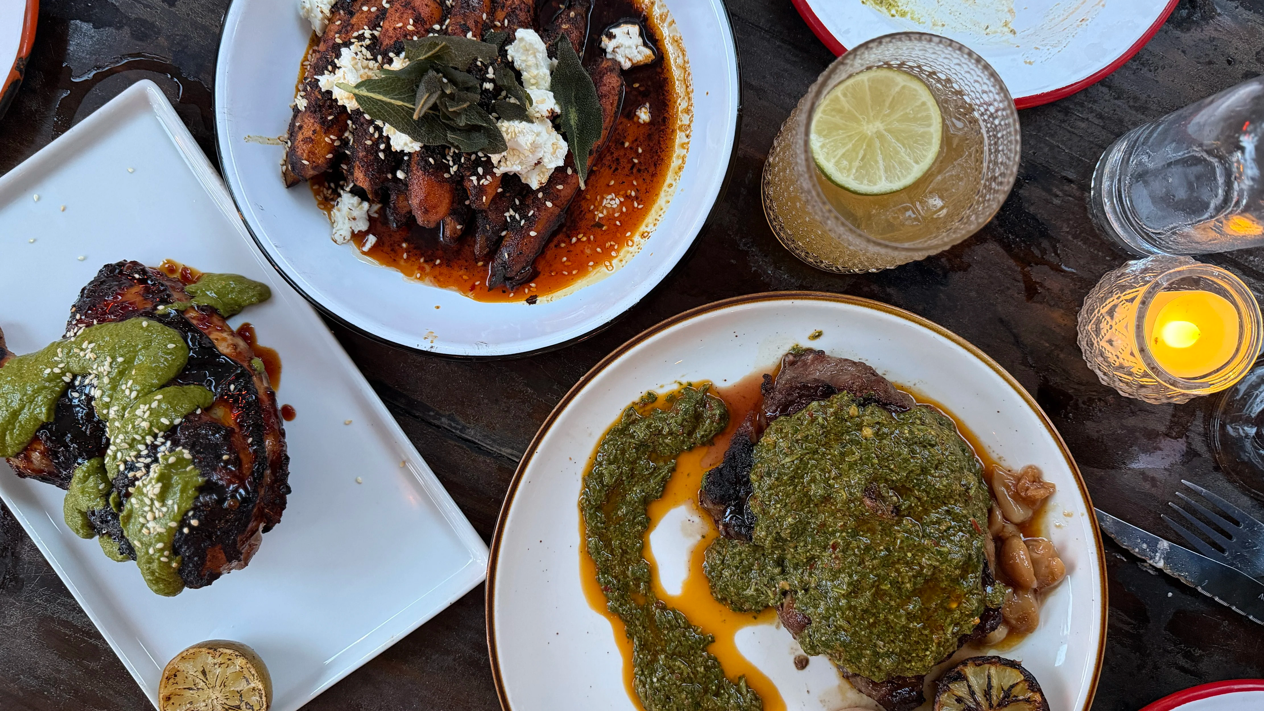 Overhead spread of charcoal grilled chicken, ribeye, and fire roasted carrots at Lost Isle on John's Island