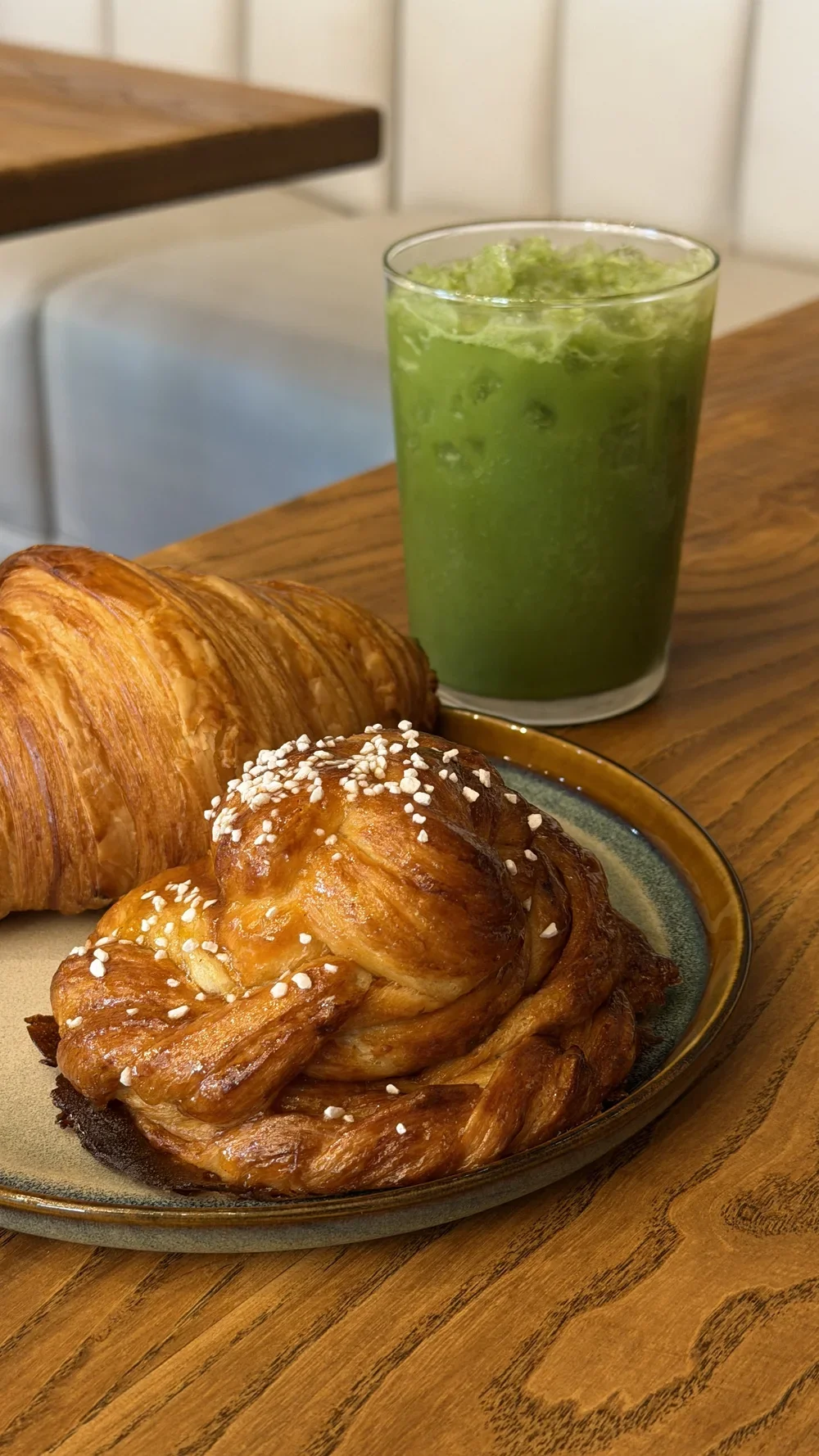 Cardamom bun with pearl sugar next to an iced Castaway matcha drink at Nine of Cups