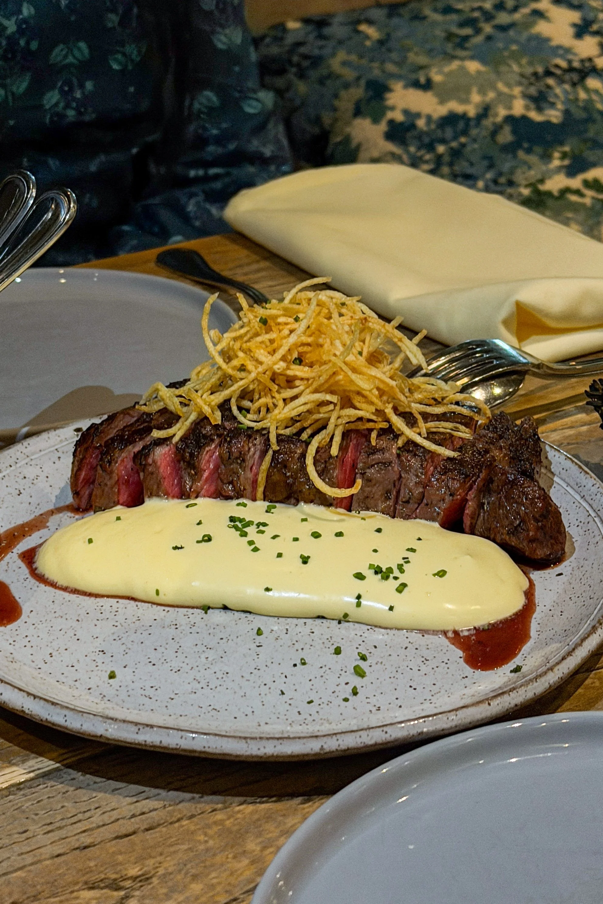 The wood-fired ribeye at J.C. Holdway in Knoxville, sliced and topped with crispy potato hay alongside an airy hollandaise foam