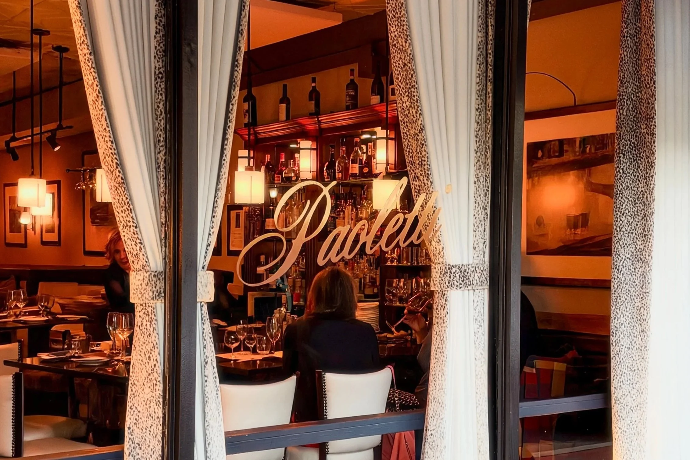 The exterior of Ristorante Paoletti, viewed through the restaurant's front window with its gold script signage.