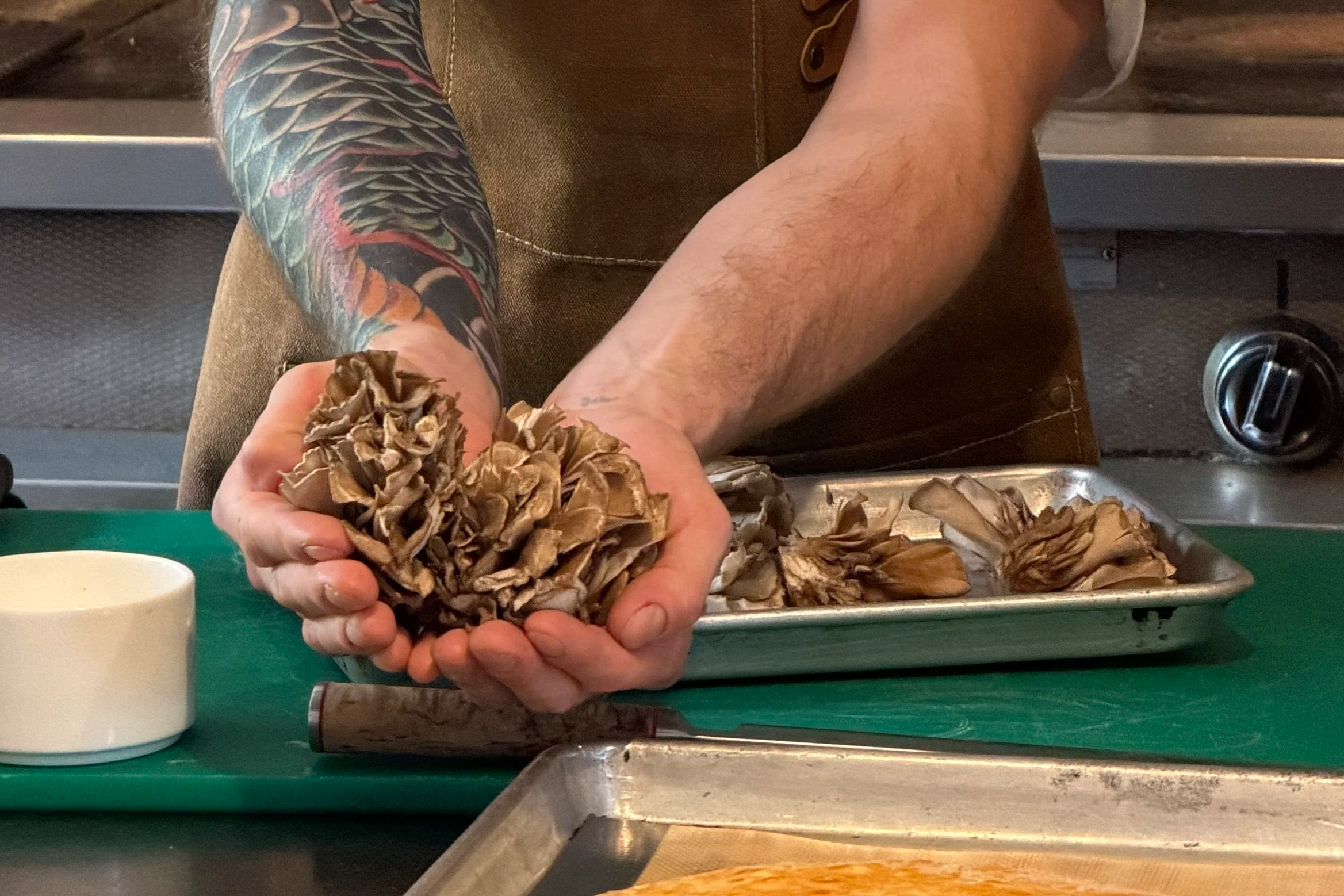 Close-up of maitake mushrooms held over a prep tray at Zero George's cooking class