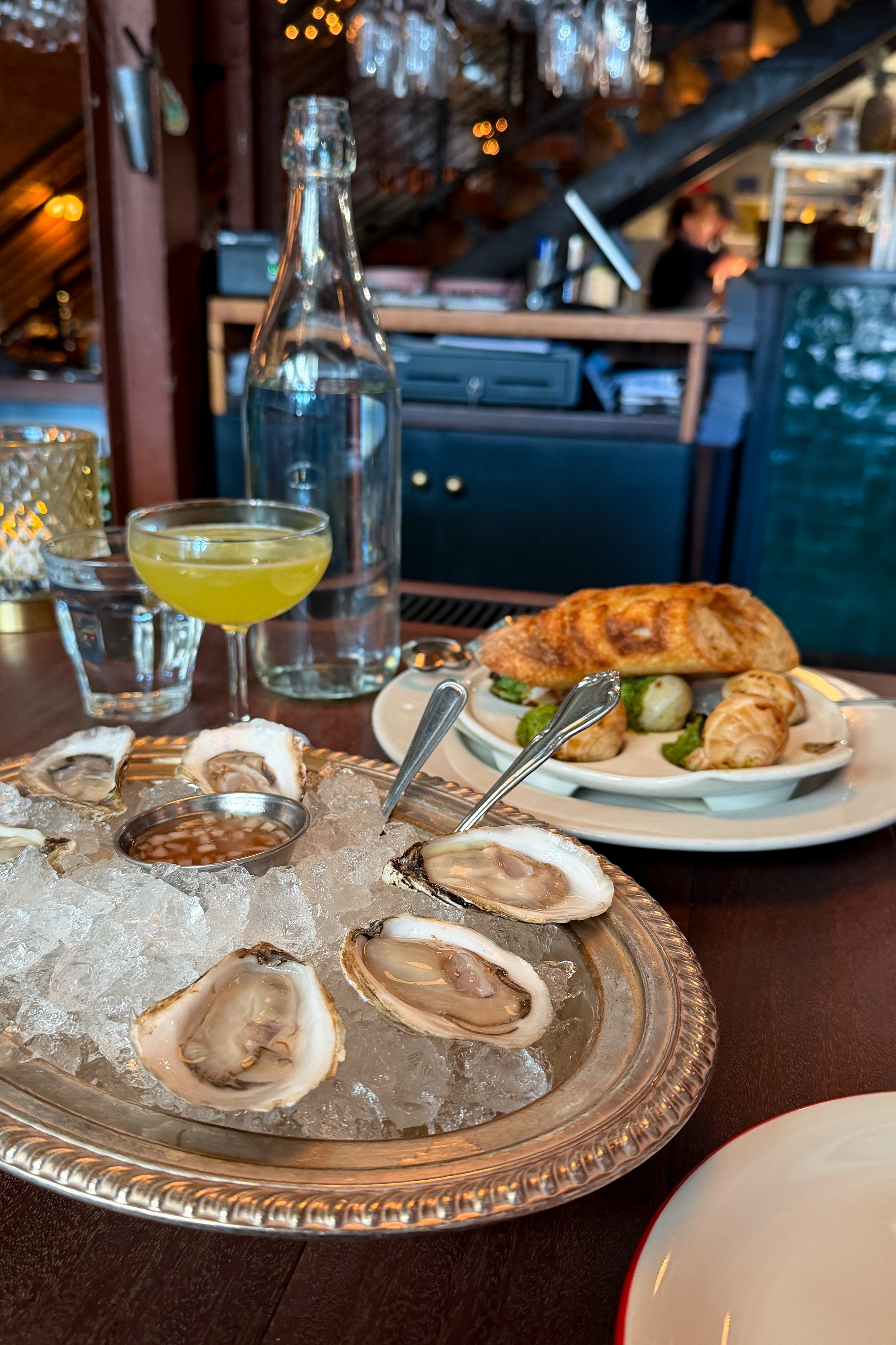 Escargot in garlic herb butter with crusty bread, served alongside a tray of oysters on ice at The Bull and Beggar in Asheville