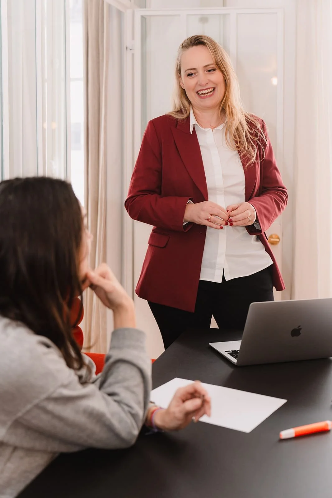 Estelle Divet parle à une autre femme assise à une table lors d'une réunion.