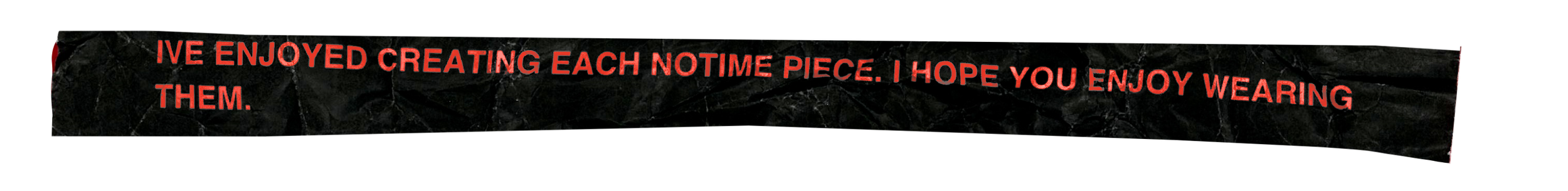 Close-up view of black textured fabric with red embroidered text that reads: "I'VE ENJOYED CREATING EACH NOTIME PIECE. I HOPE YOU ENJOY WEARING THEM."
