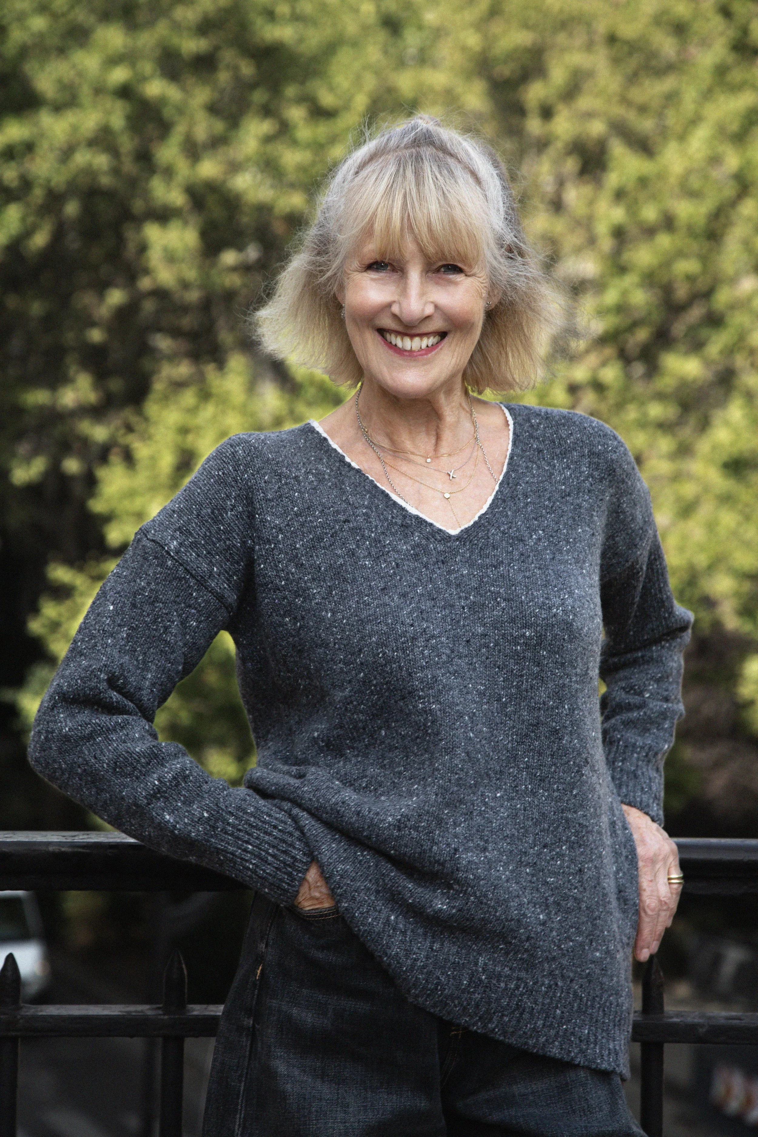 Jane is wearing an oversized speckled grey cashmere blend sweater with a white ribbon trim, beautifully crafted in Italy.