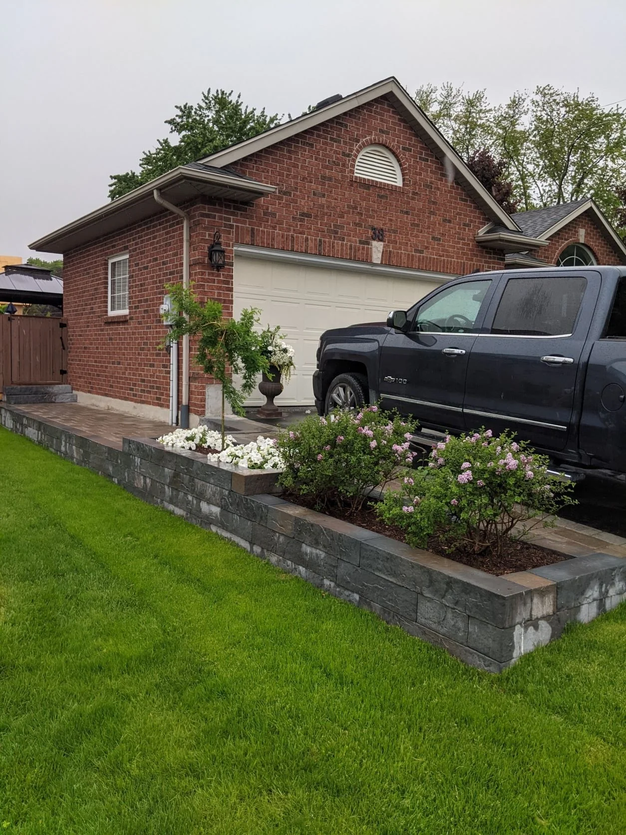 Techo-Bloc Rocka raised planter and retaining wall bordering a Unilock Brussels interlock walkway in Fonthill.