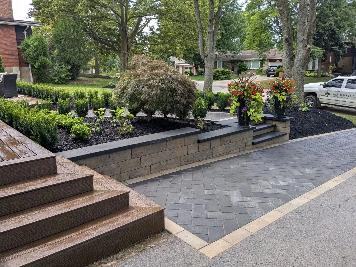 Modern St. Catharines front yard walkway featuring a retaining wall and steps made from Techo-Bloc's Brandon wall and Blu 80 pavers in a herringbone pattern