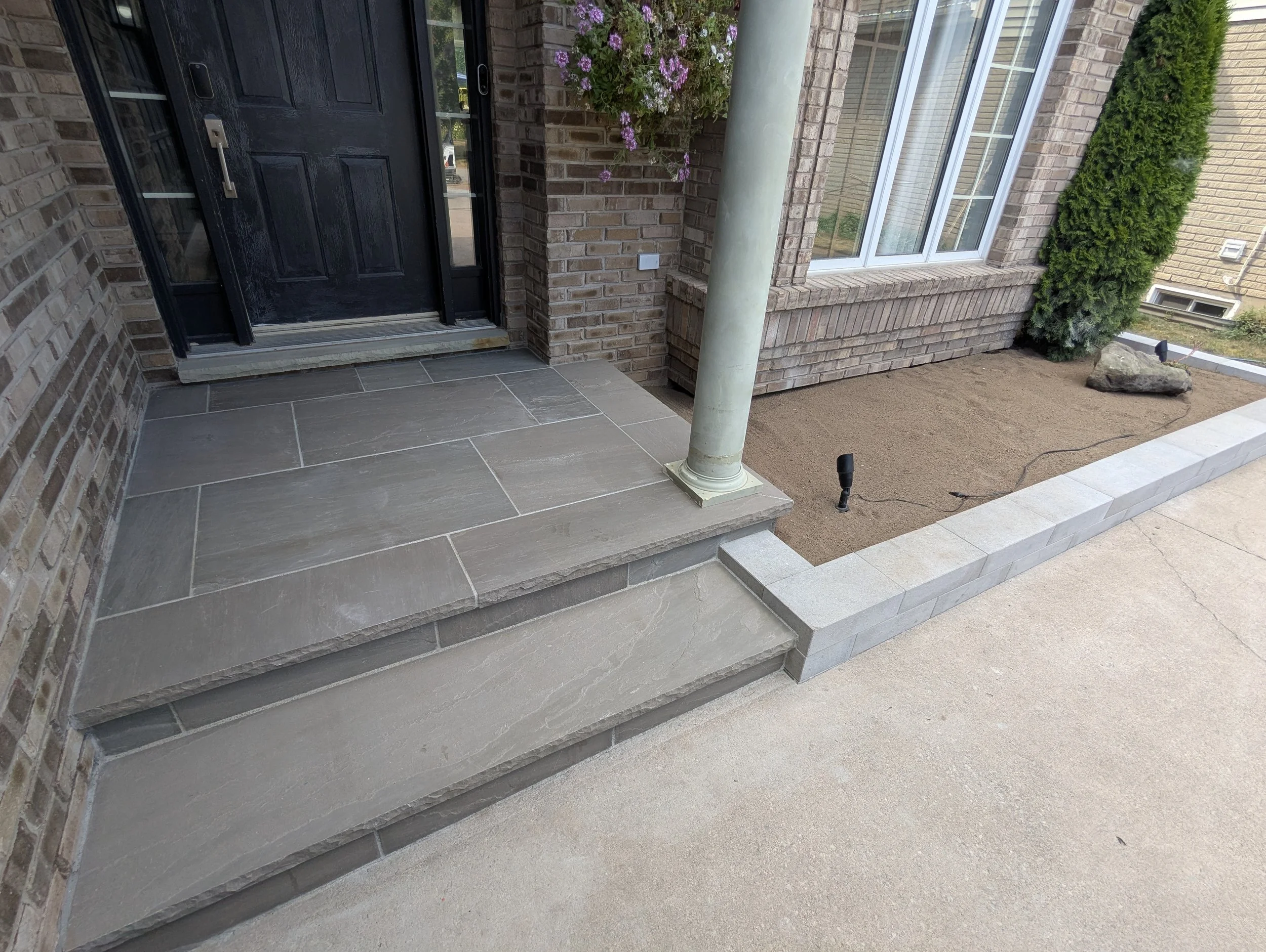 A newly installed front entrance in Fonthill featuring Oakville Stone's Slate Grey square cut flagstone and stair treads.