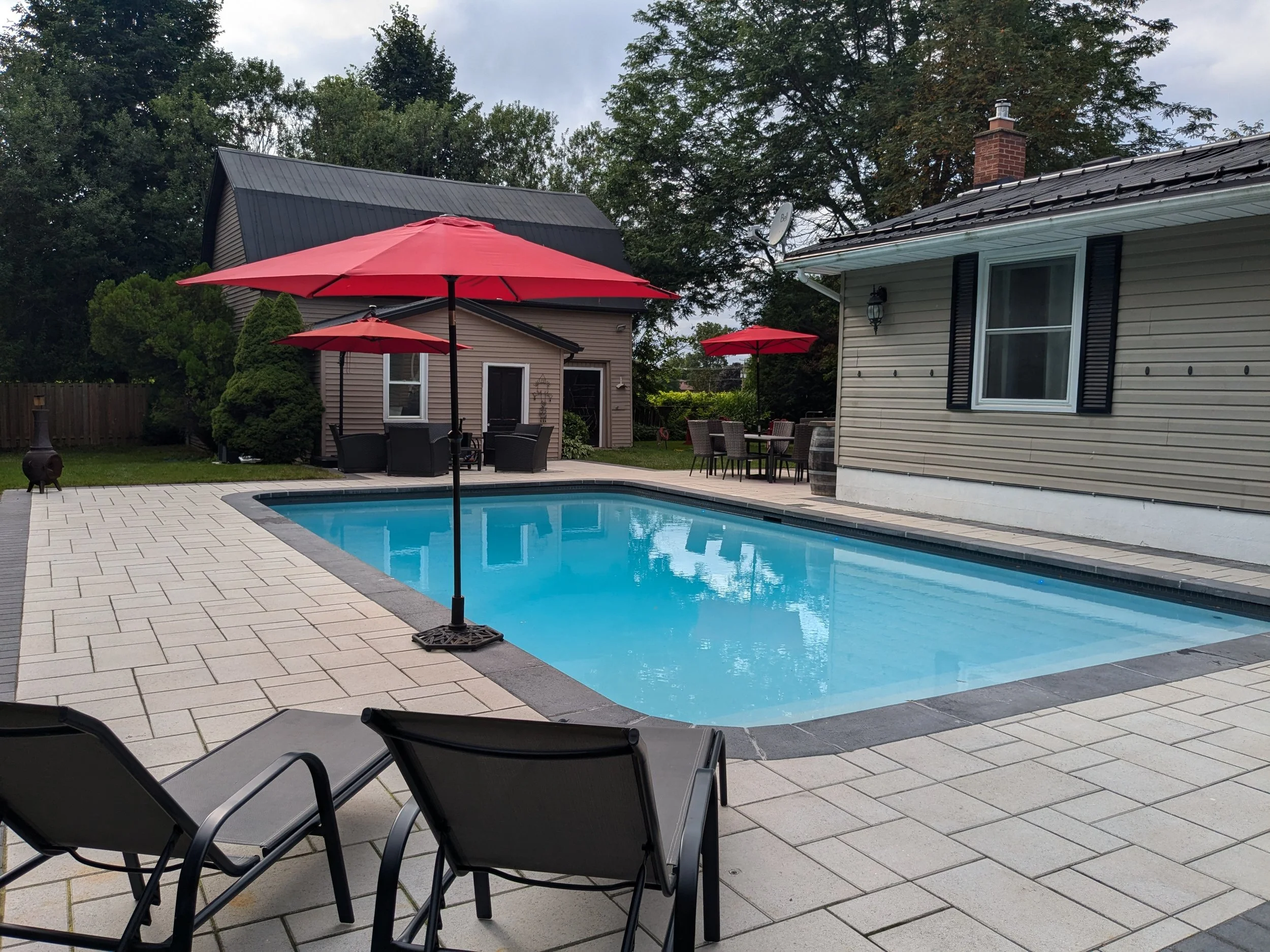 Modern pool patio design featuring Techo-Bloc Blu 60, professional pool coping, and a multi-functional outdoor living space with integrated dining and lounge areas in Jordan.