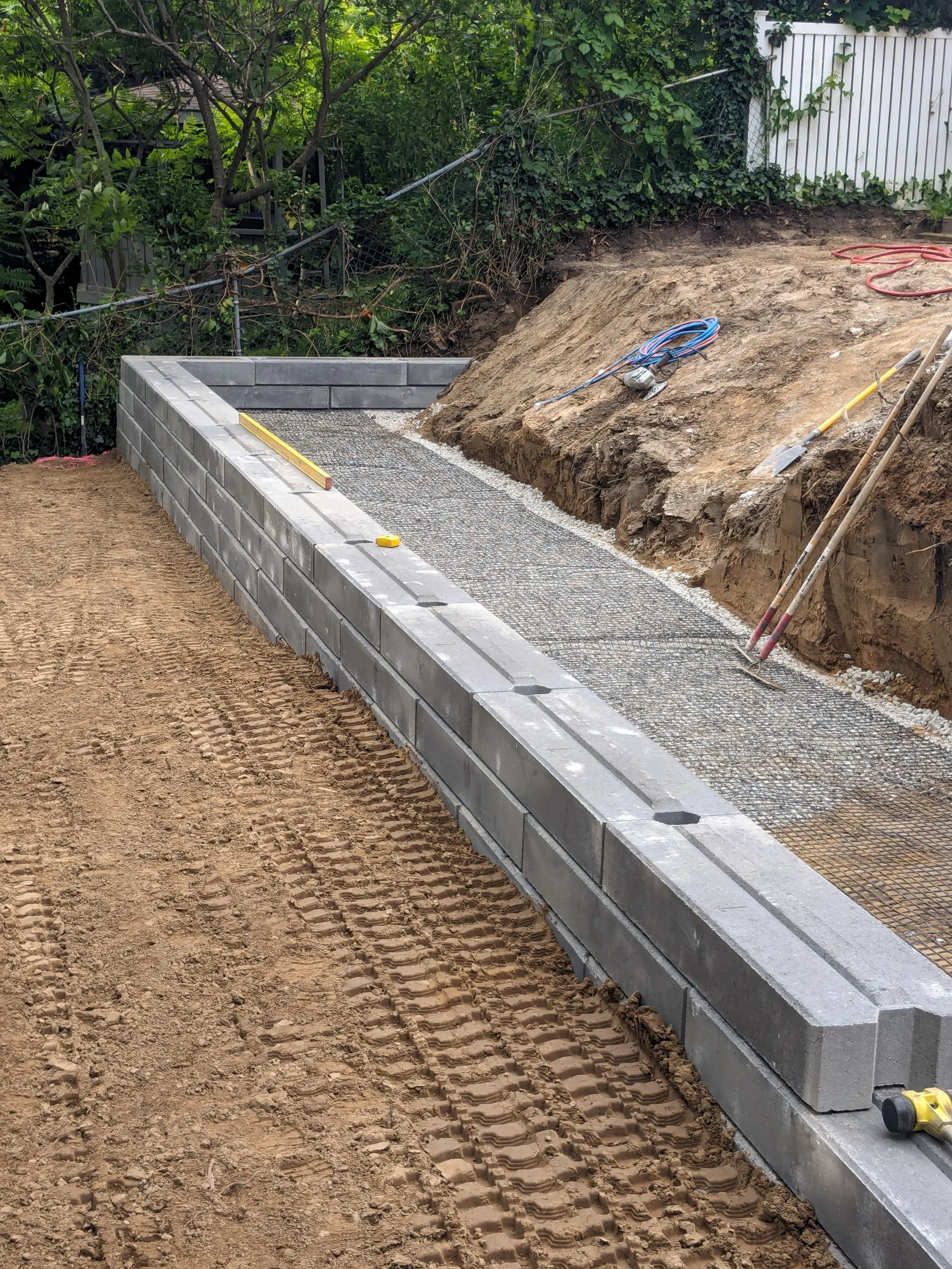 Modern Unilock Siena Stone retaining wall installation with geogrid reinforcement and professional site grading.