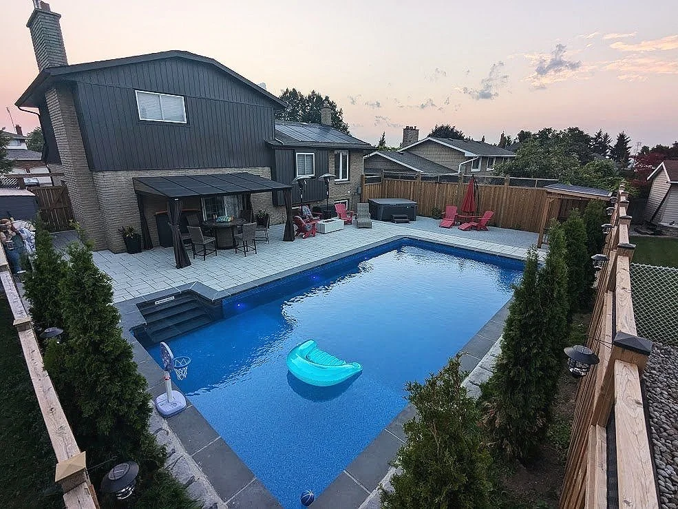 Professional interlock pool deck installation in St. Catharines featuring Techo-Bloc Blu 60 pavers in a modern pattern, surrounding a rectangular inground pool and custom fire pit lounge.