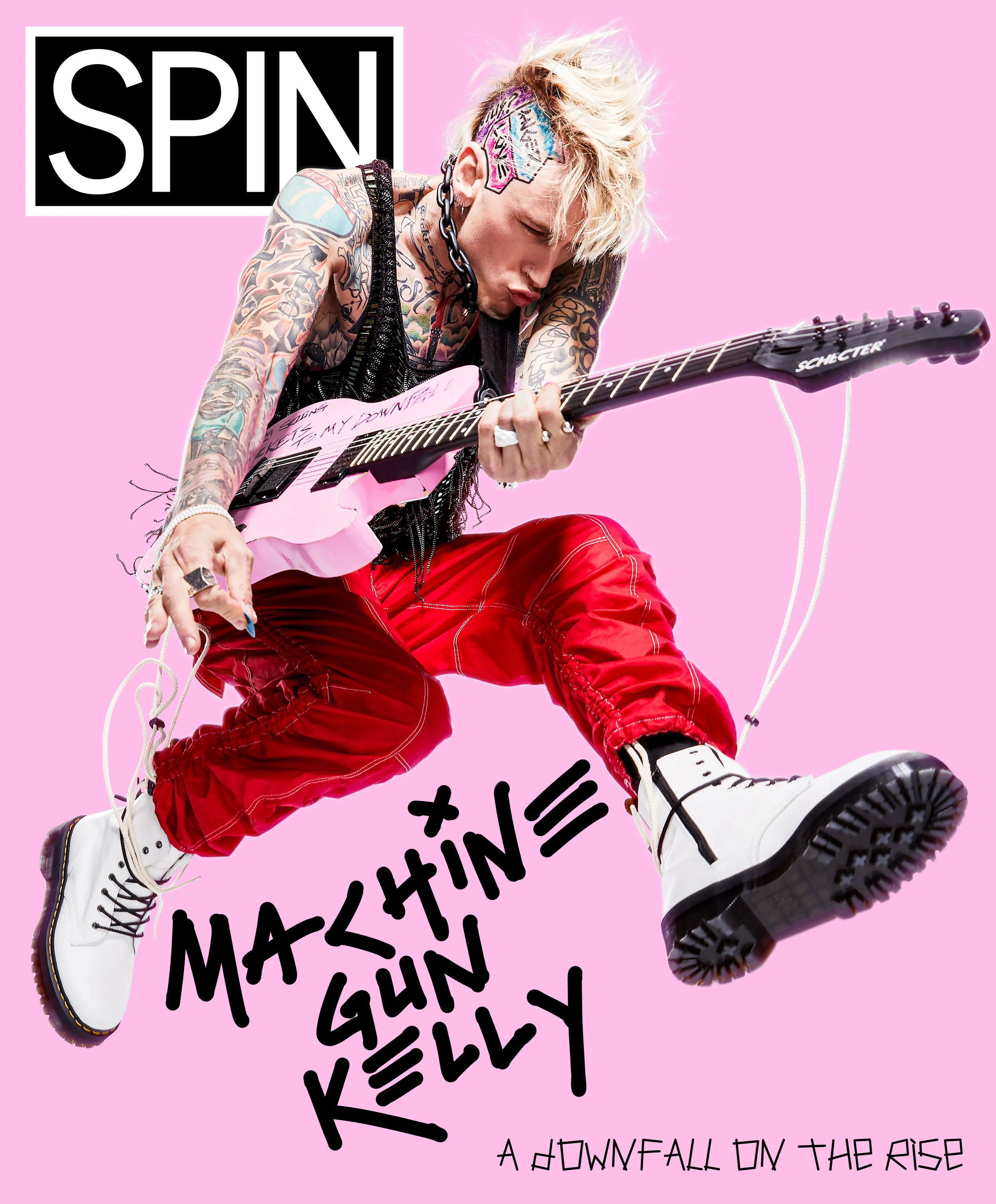 A person with tattoos and blonde hair playing a pink guitar, wearing red pants and white boots, on a pink background with the words 'Spin' in a black box and 'Machine Gun Kelly' and 'A Downfall on the Rise' written in stylized black text.