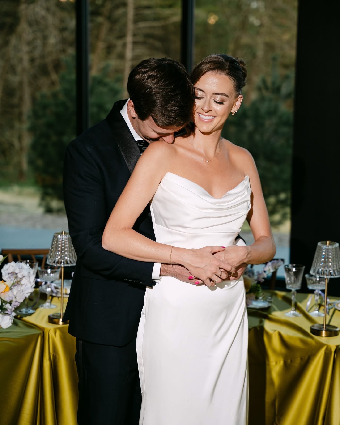 Flash photo of a bride and groom together while the groom kisses his bride's shoulder