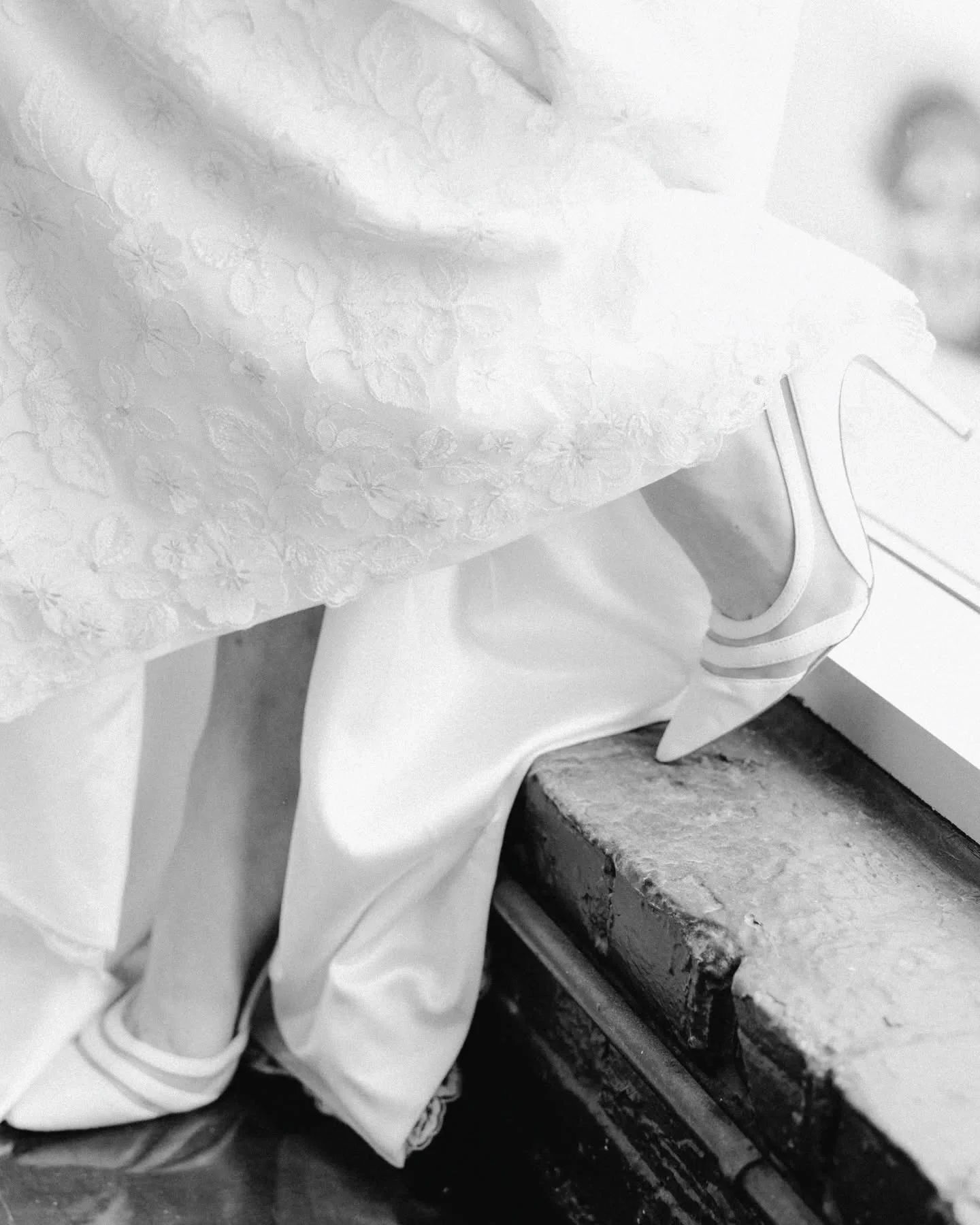 Black and white image of brides shoes as she steps down stairs