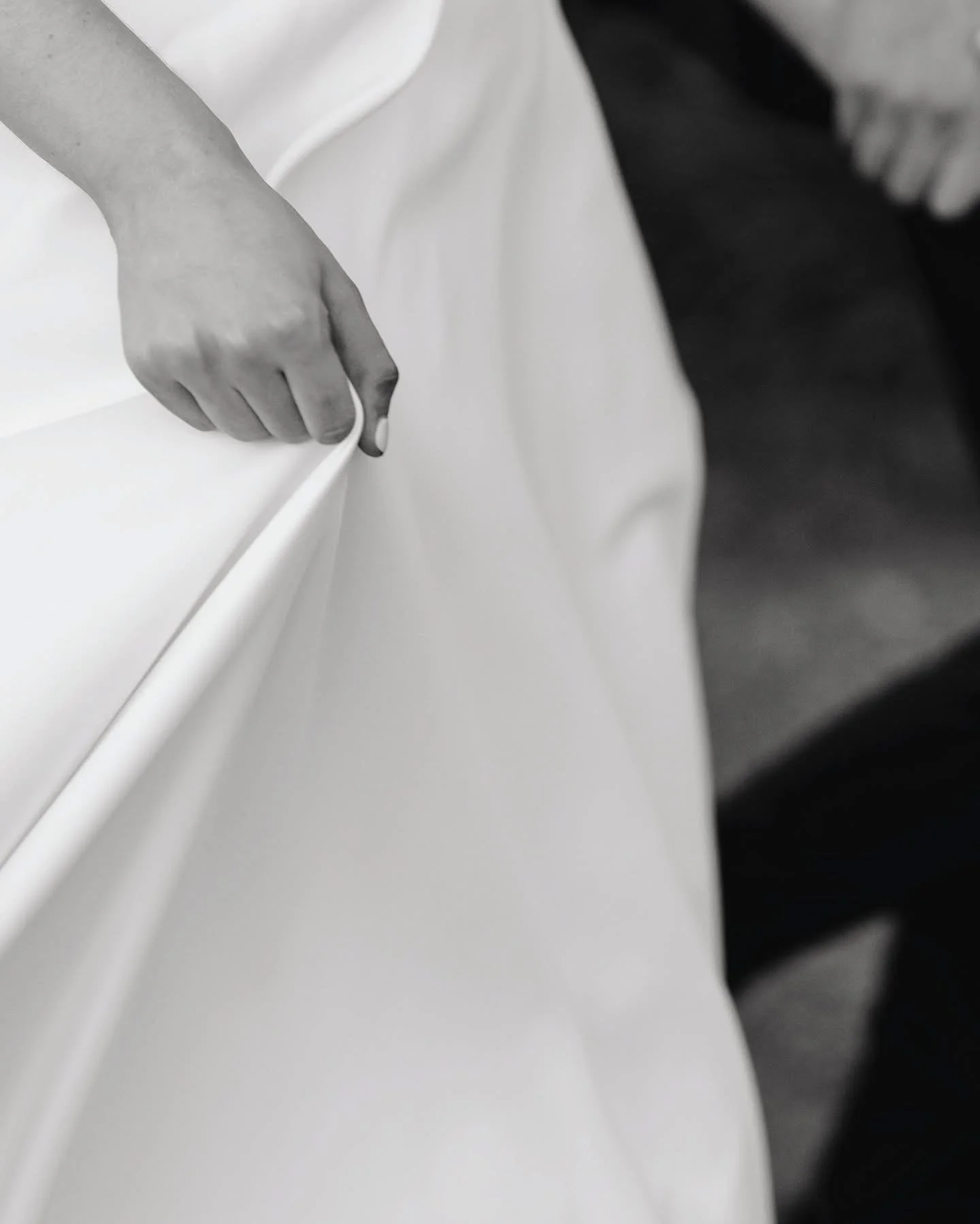 Close up black and white image of brides hand holding her dress skirt