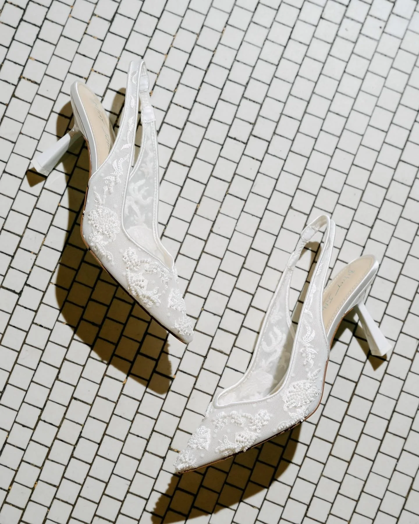 White lace wedding heels on a white tile floor