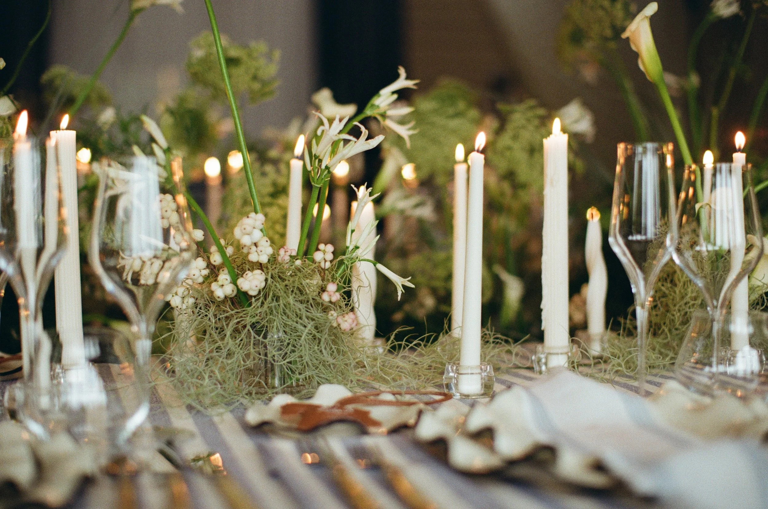 Lush green wedding tablescape with candles lit