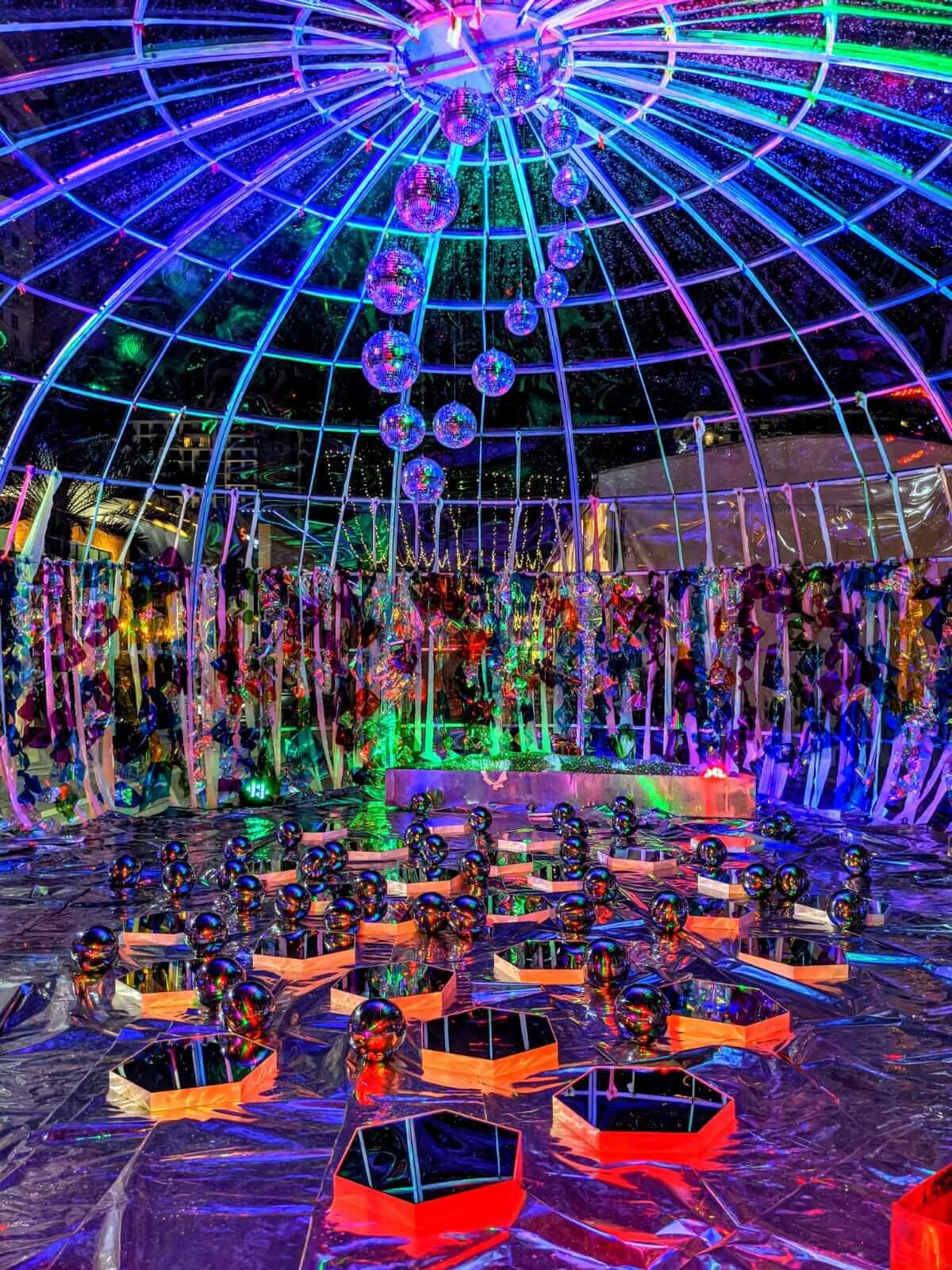 Neon art installation in bubble event space full of green, blue, and purple lighting