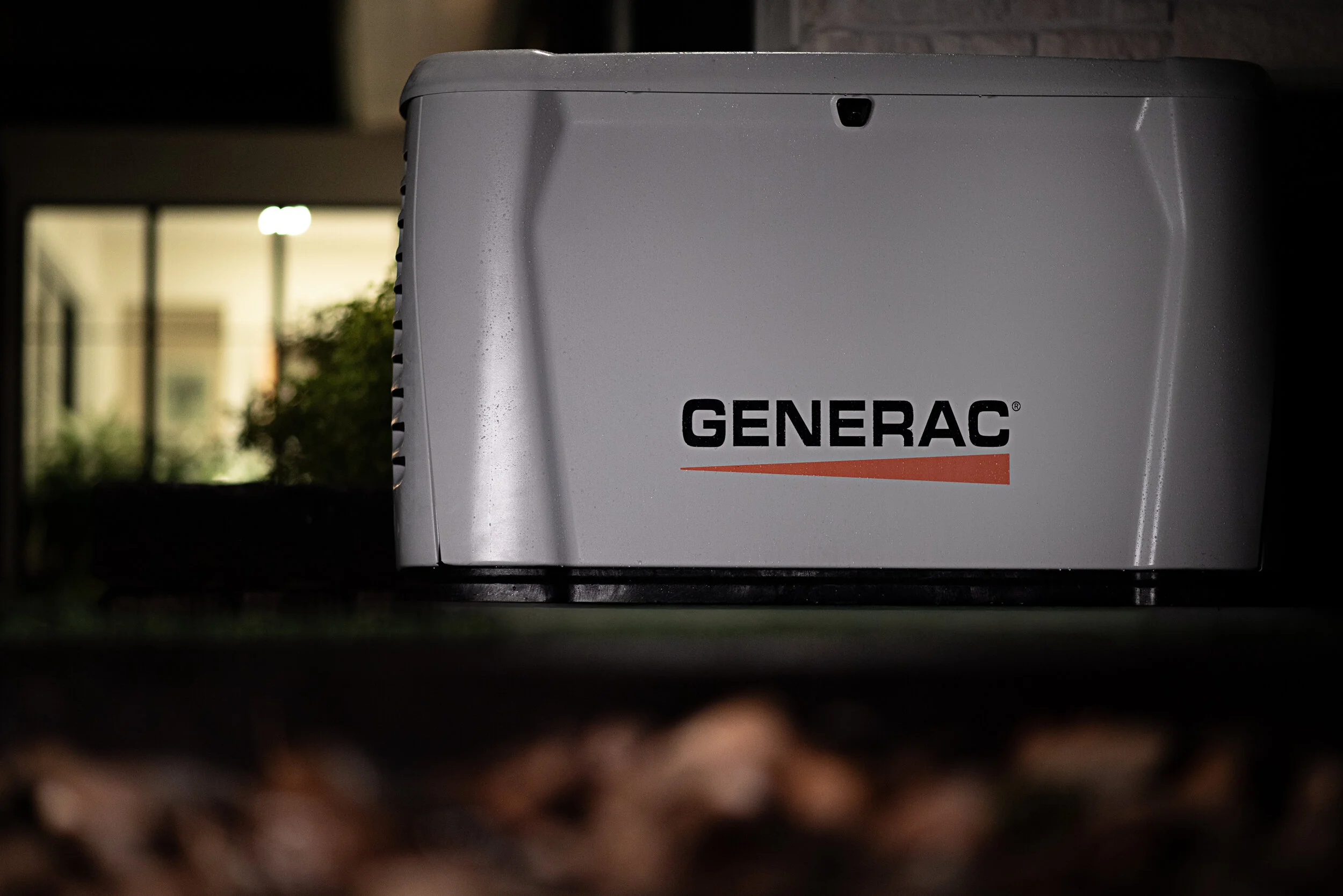 A white Generac generator outdoors at night.