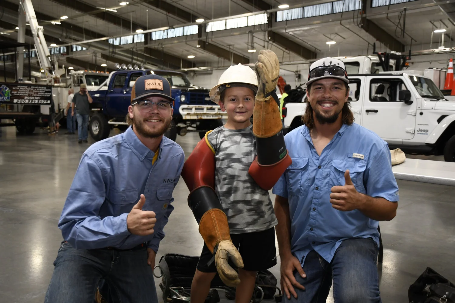 Two NWEC linemen with a young member at a community event