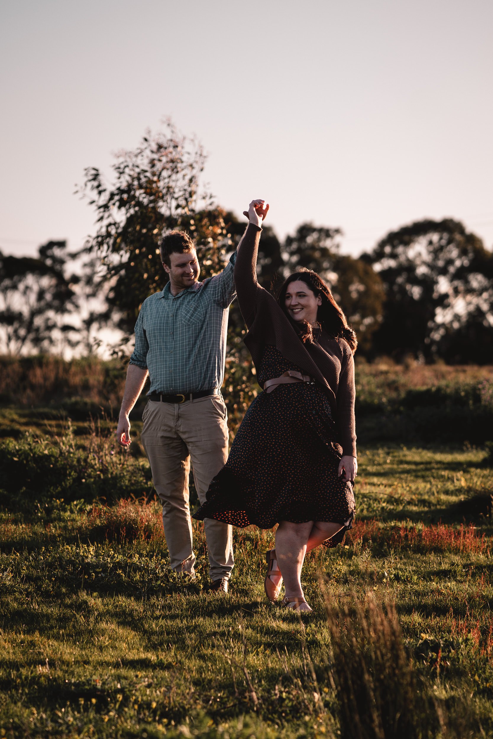 Couple dancing outdoors at sunset in a grassy field