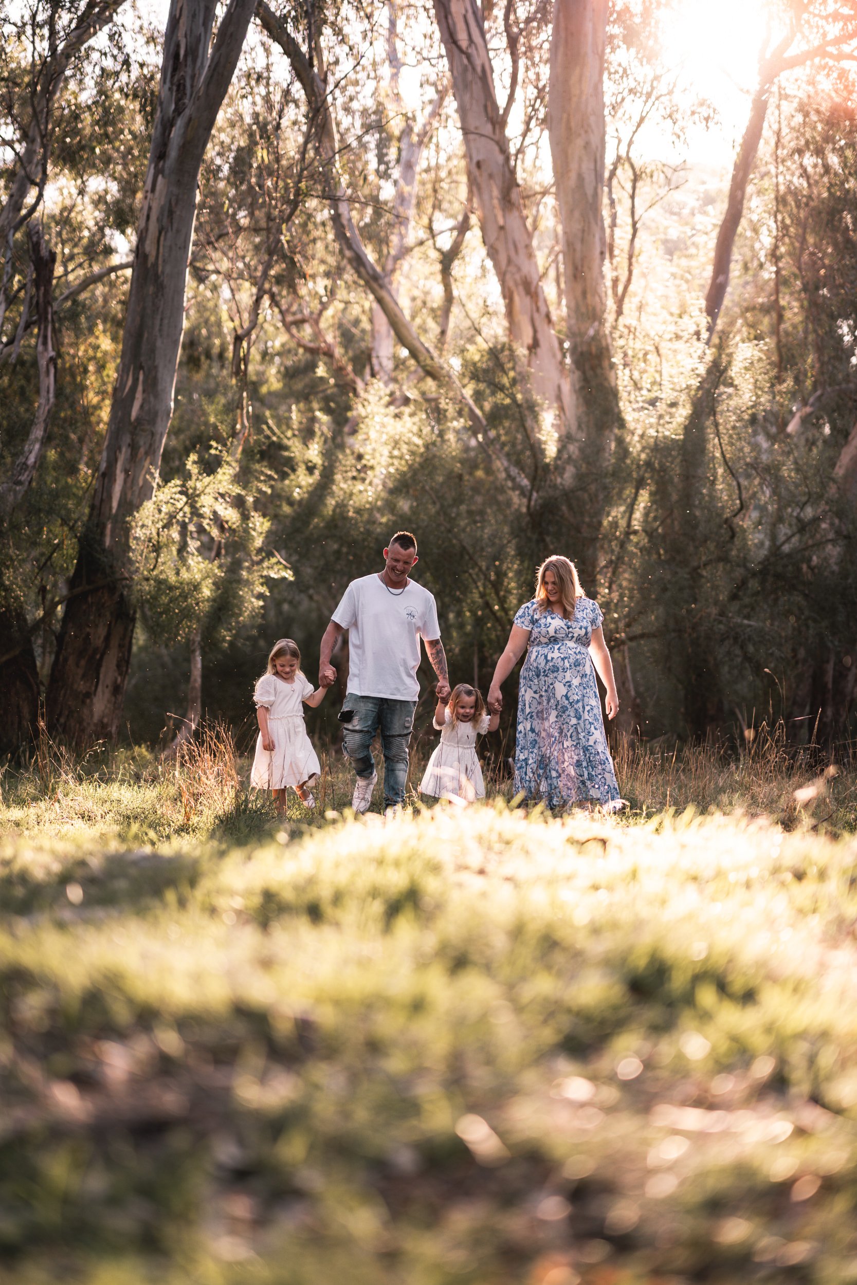 Family walking in sunlit forest with trees and grass