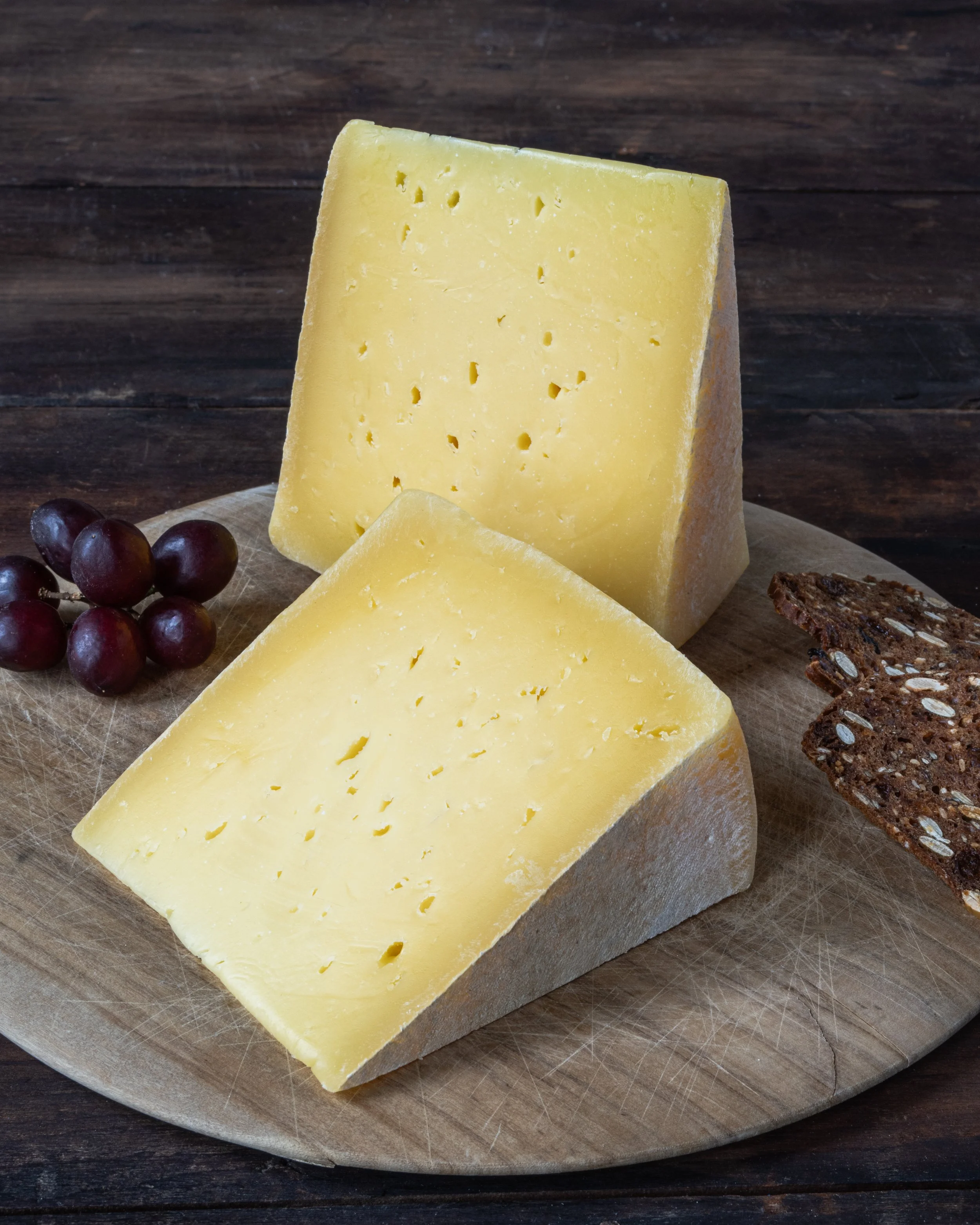 artisan cheese on wood board with crackers and grapes