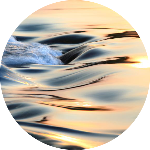Close-up of water with gentle ripples and reflections of sunlight during sunset or sunrise.