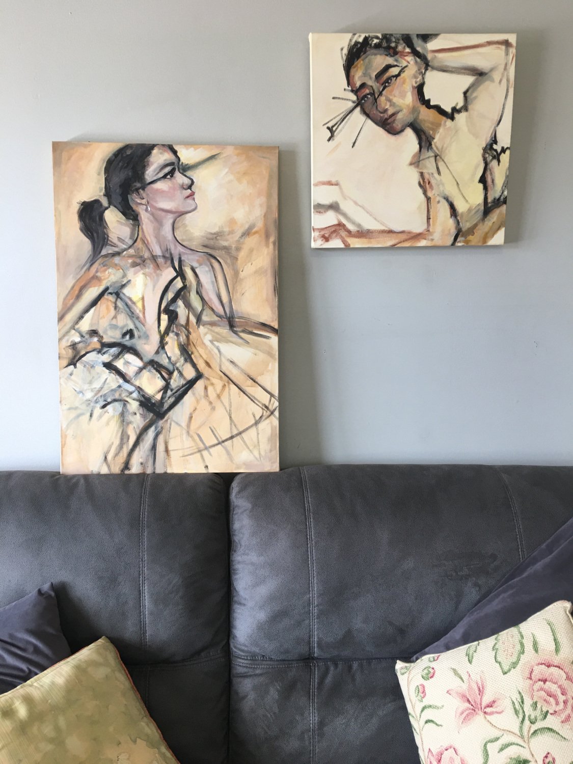 A painting in acrylic on canvas of a woman. Her face is framed with a black outline and the painting has shades of cream and beige. Very fashion illustration aesthetic. Styled shot with couch.