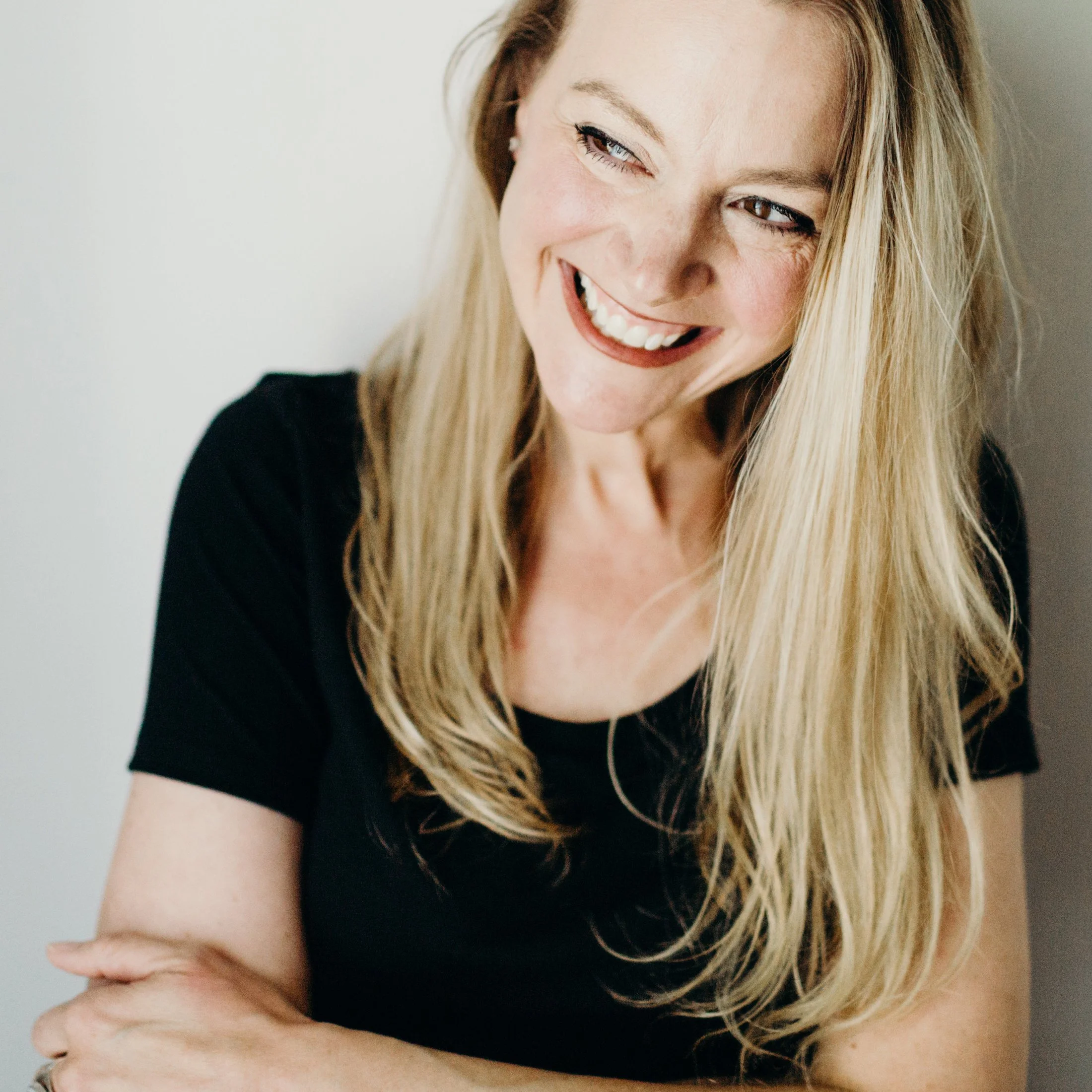 Kristin Robertson standing against a beige wall and looking to her right.