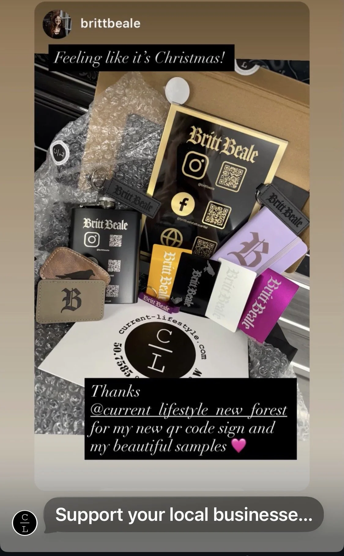 Display of branded promotional items for Britt Beale, including business cards, stickers, keychains, and samples, with Instagram and Facebook QR codes and logos. Lasered corporate gifts.