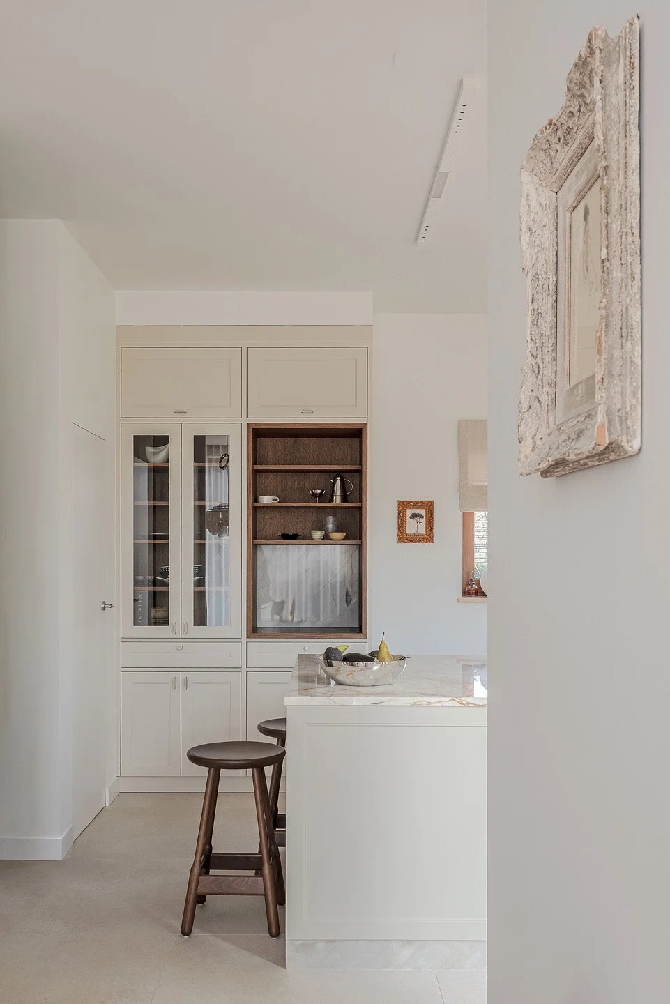 Realizacja jasnej, eleganckiej kuchni z wyspą. Aranżacja wnętrz Warszawa – THE LINE STUDIO. Beżowe meble w stylu klasycznym. Kamienny blat  z wzorem, drewniane krzesła i subtelne dodatki. Zobacz kompleksowe projektowanie wnętrz i unikalne projekty wn