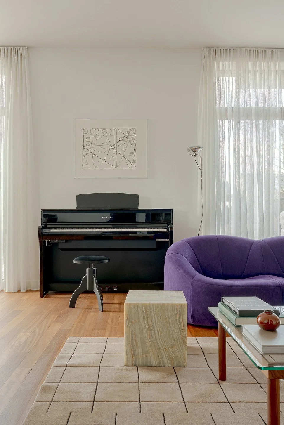 Projektowanie wnętrz w Warszawie od THE LINE STUDIO. Realizacja salonu w otwartej strefie dziennej. Przestronna aranżacja wnętrz łączy elegancką, fioletową sofę z nowoczesnym piecem kaflowym. Unikalne projekty wnętrz THE LINE STUDIO to dialog między 