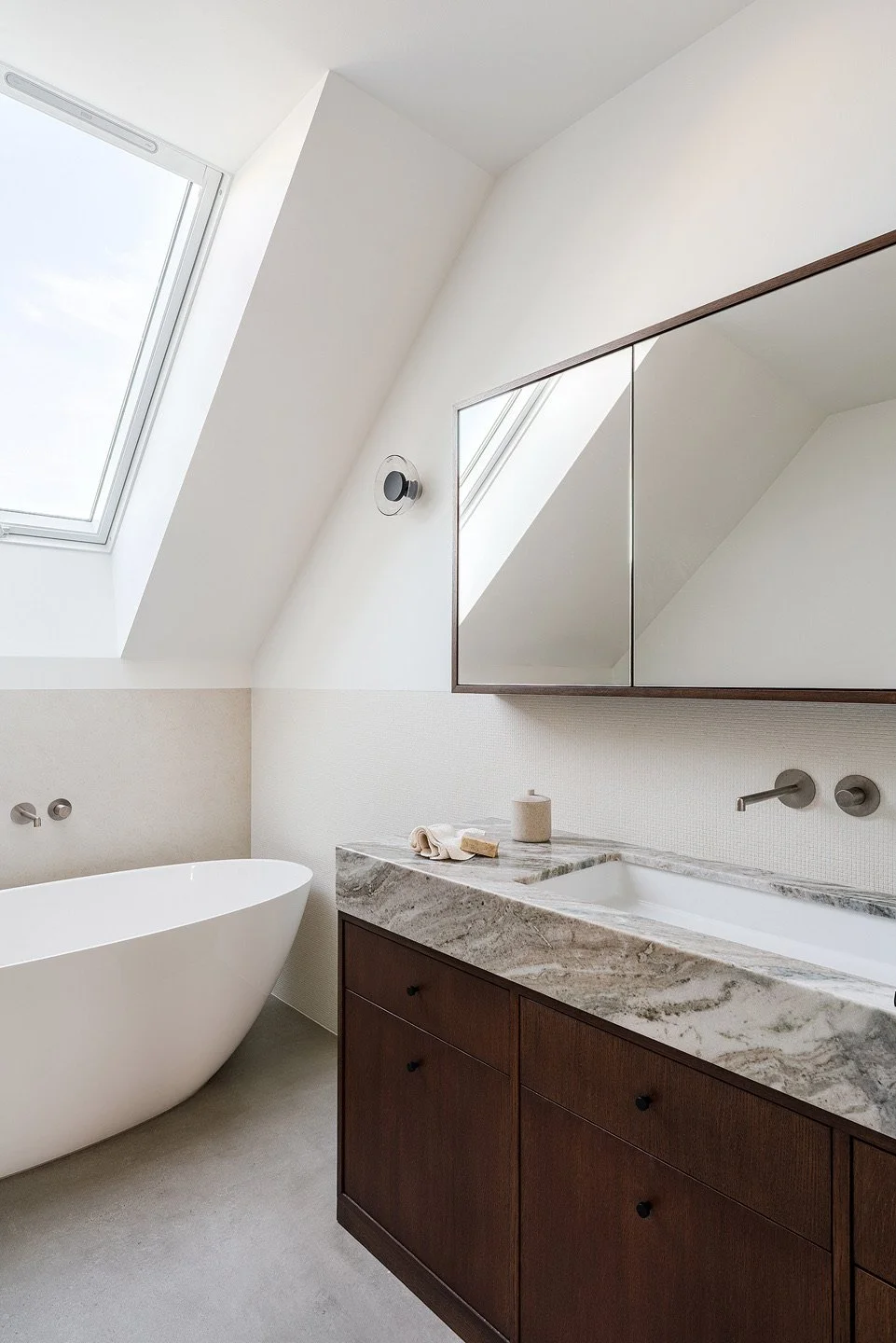 Projektowanie wnętrz łazienek w duchu domowego SPA od THE LINE STUDIO. Prezentujemy salon kąpielowy z wanną wolnostojącą umieszczoną bezpośrednio pod oknem dachowym. Nasze autorskie projekty wnętrz Warszawa łączą chłód naturalnego kamienia z ciepłem 