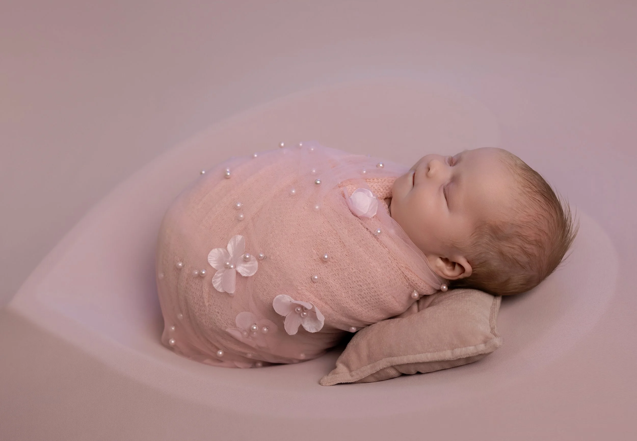 baby sleeping in a heart bowl on a photoshoot