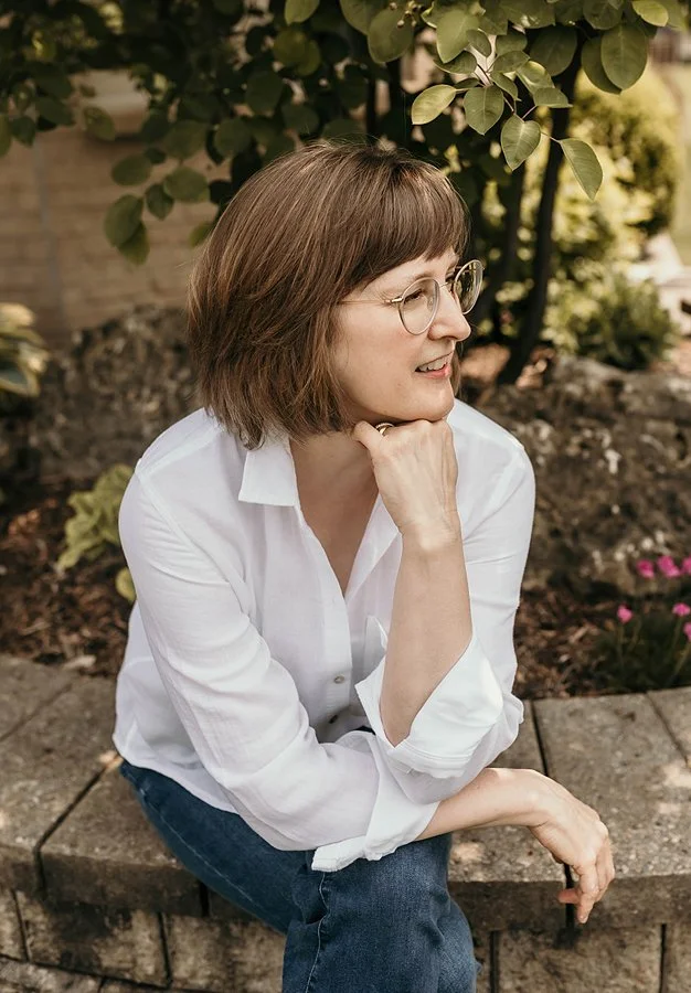 The artist Ann Roth sitting outside surrounded by greenery.