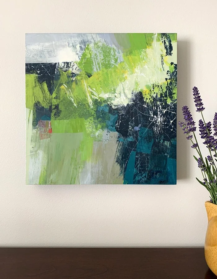 An abstract painting in Kelly green and Oxford blue with a vase of lavender.