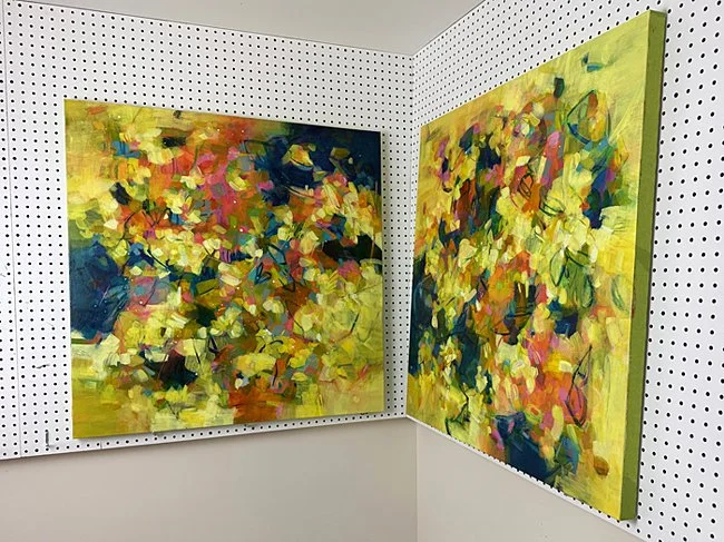 Two large, mostly yellow paintings on the pegboard painting wall in the studio.