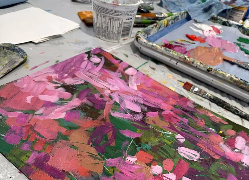 A mostly pink painting in progress at my workstation alongside palette and brush.