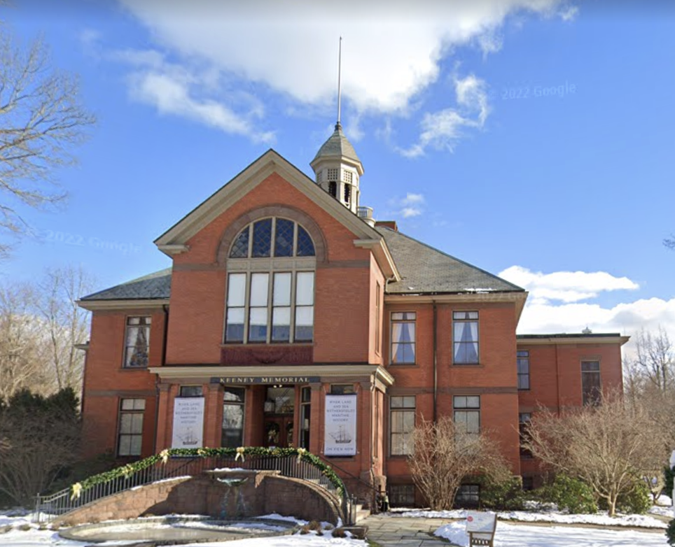 Brick church building with a spire, large arched windows, and a sign reading 'Henry Memorial,' with snow and leafless trees in front, under a blue sky with clouds.