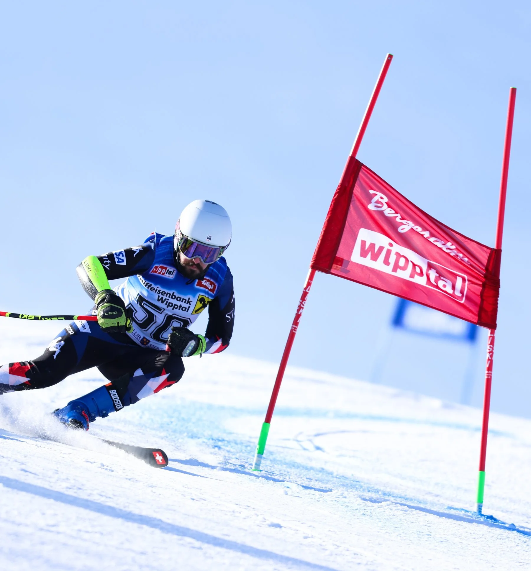 Tyler McKenzie racing giant slalom past a red gate, one pole in his right hand